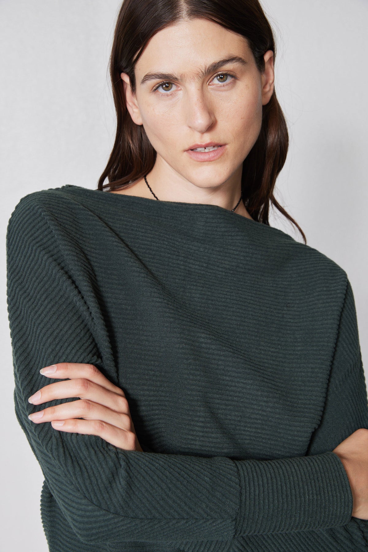 Brushed rib dolman top close-up, dark green ribbed knit texture