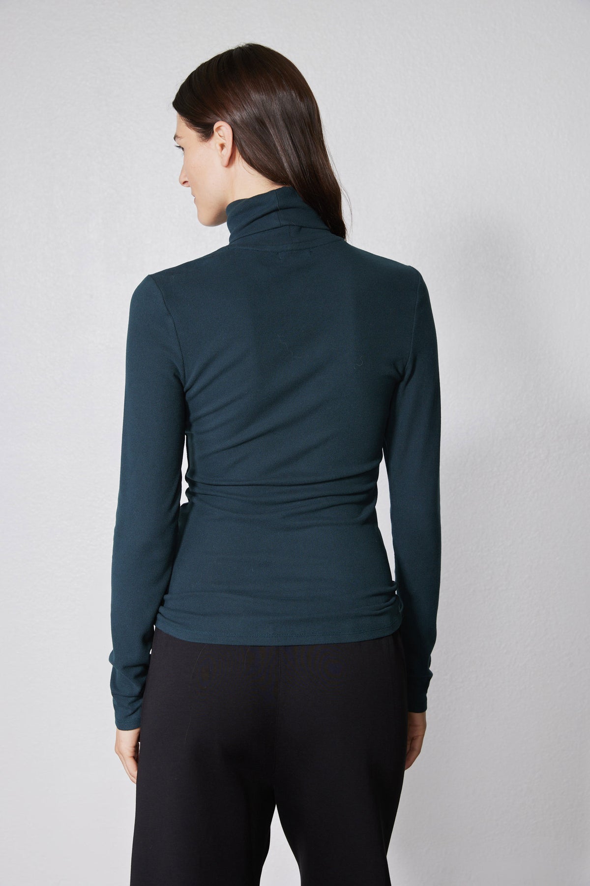 Forest green ribbed turtleneck top, long sleeves and high collar from behind