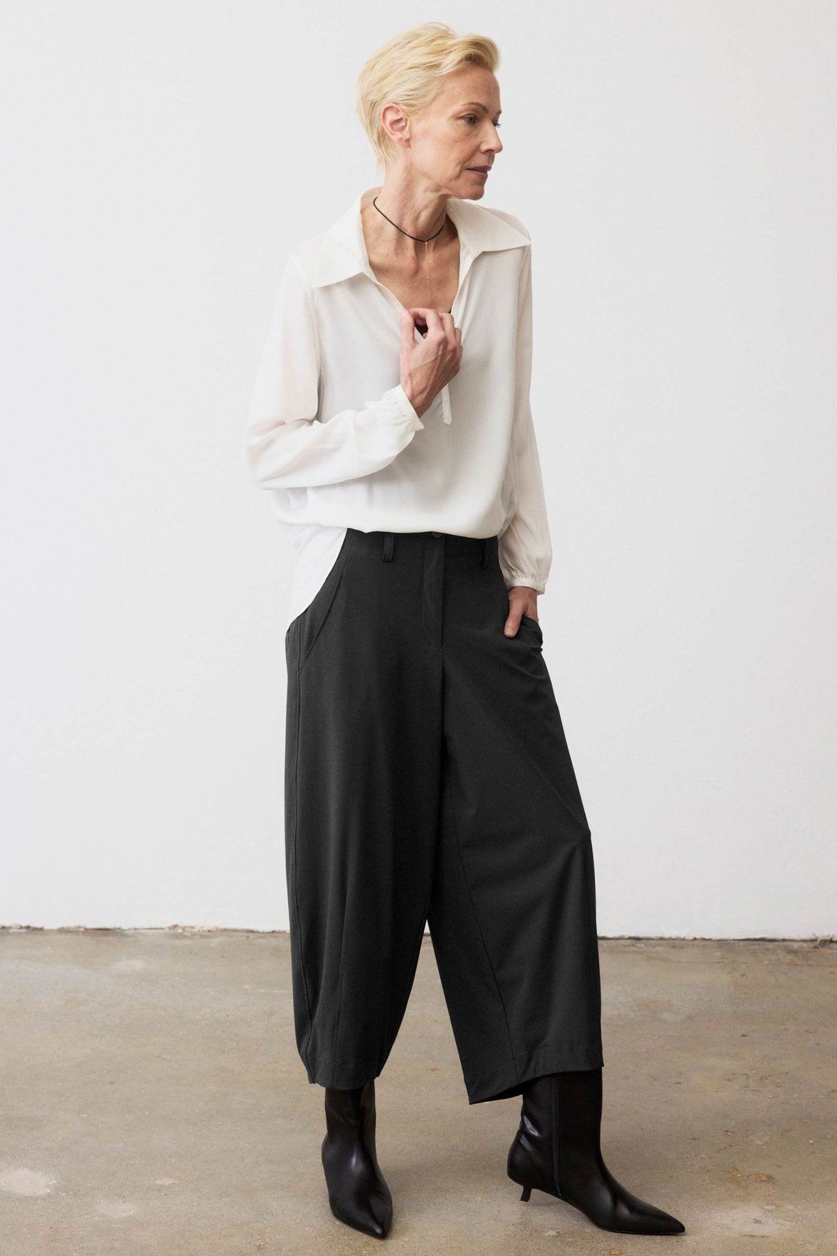 Black wide-leg pants with pleated front, elastic waistband, and roomy wide legs.