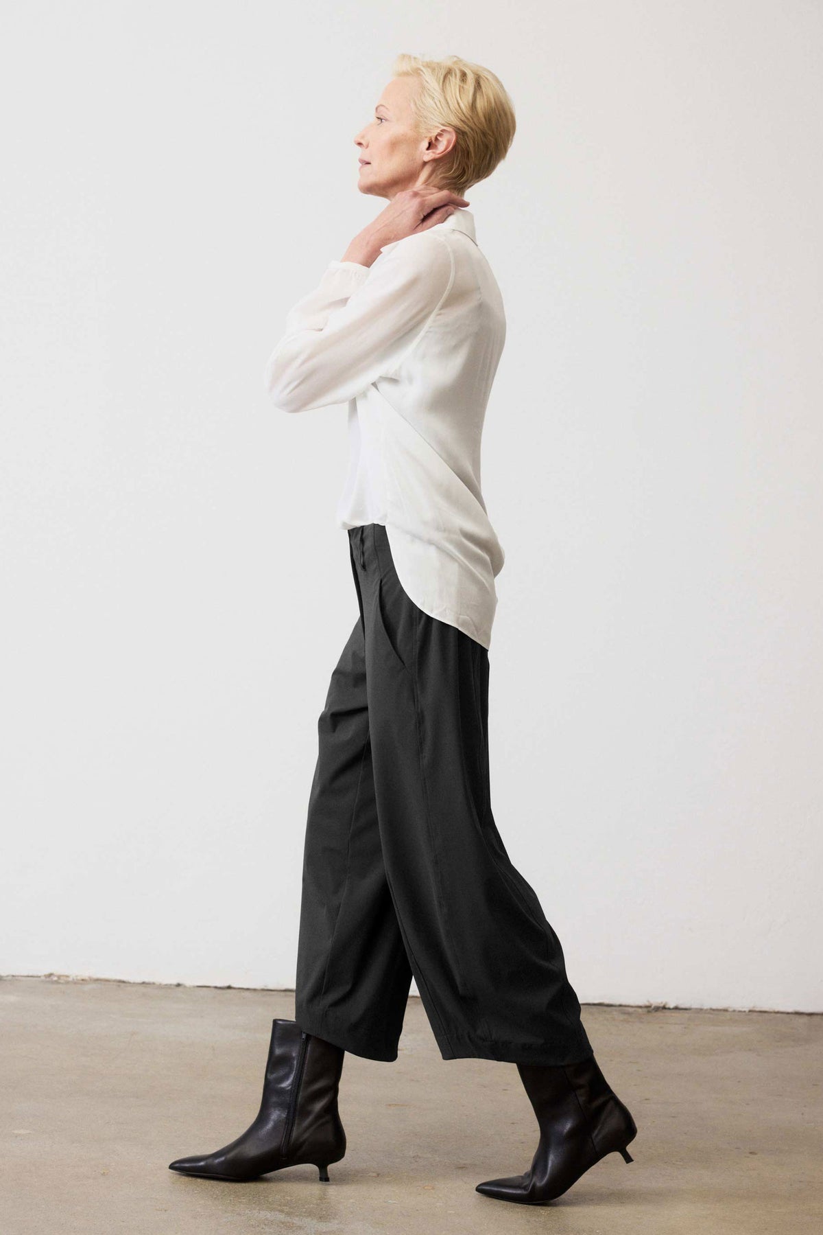 Black wide-leg pants, side profile, elastic waistband with wide draping legs.