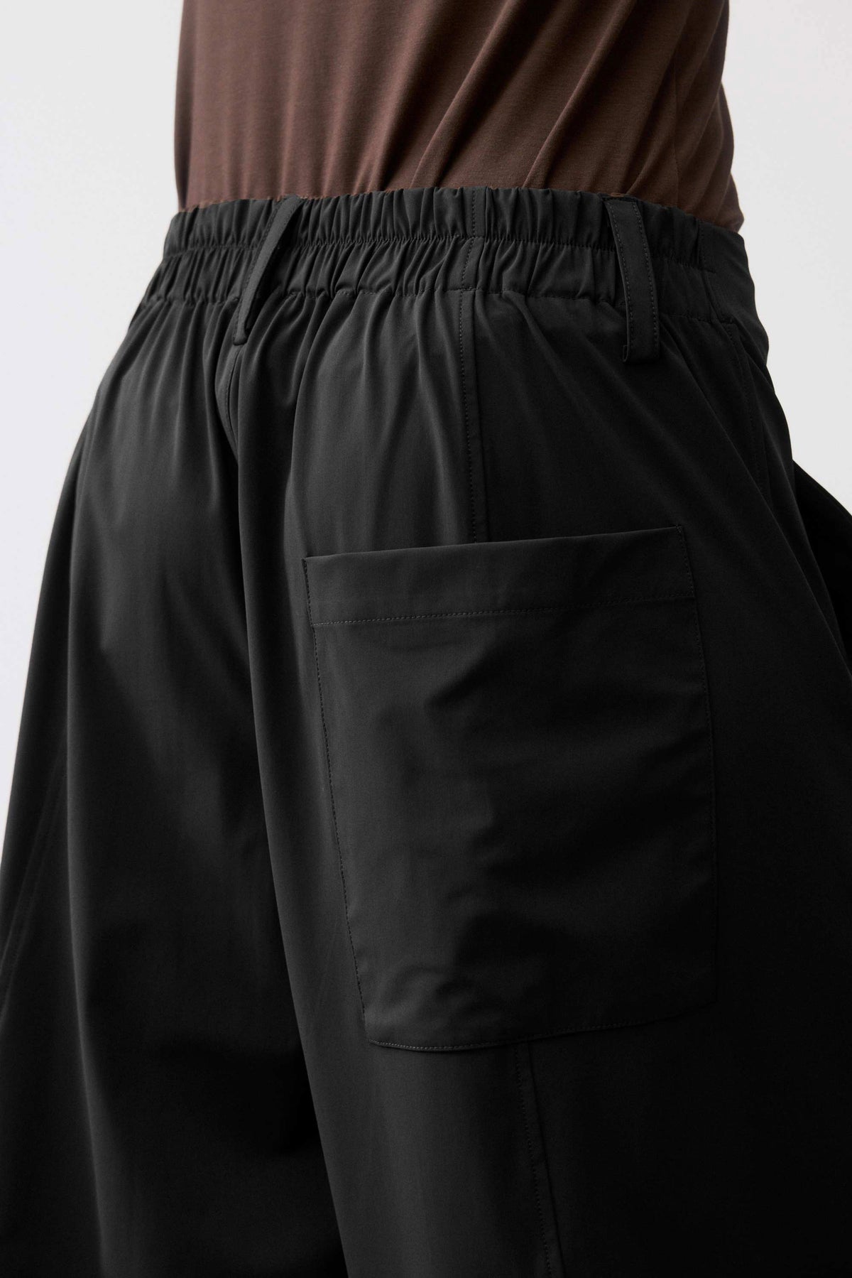 Close-up of black elastic waistband and front pocket on wide-leg pants.