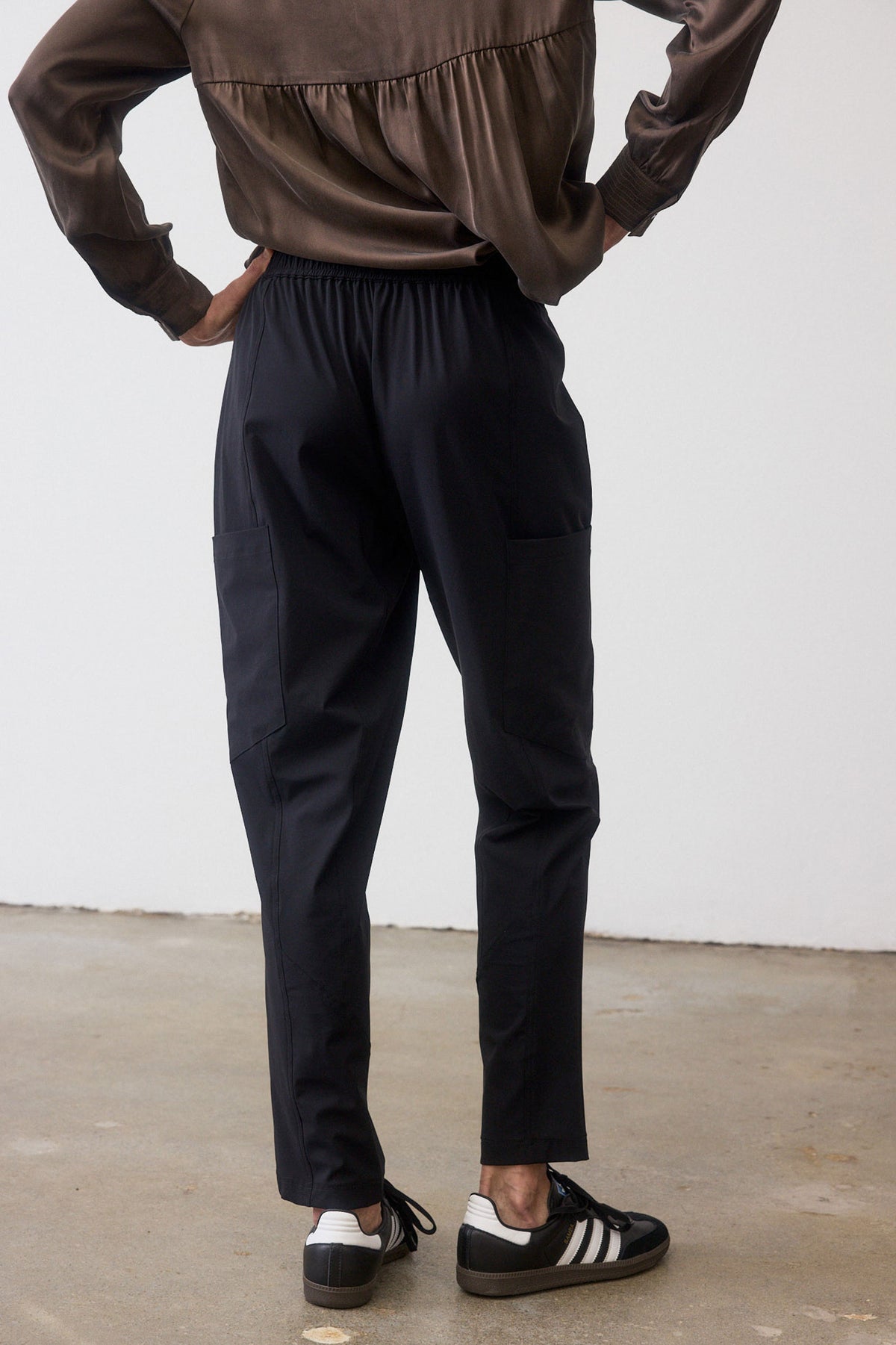 Black cargo pants back view with elastic waistband and ankle-length tapered legs.