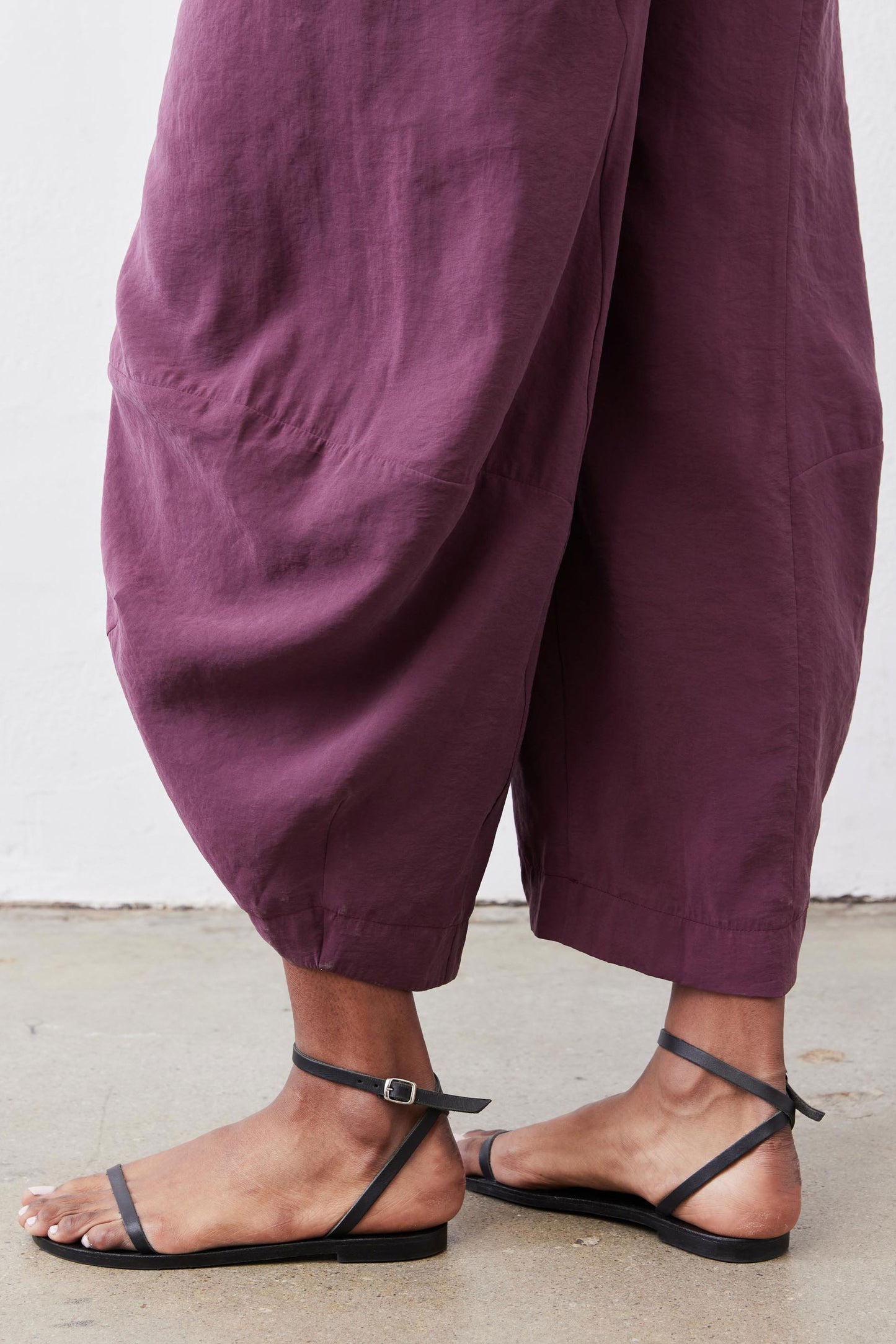 Deep purple wide-leg pants with pleated drape and ankle-length hem