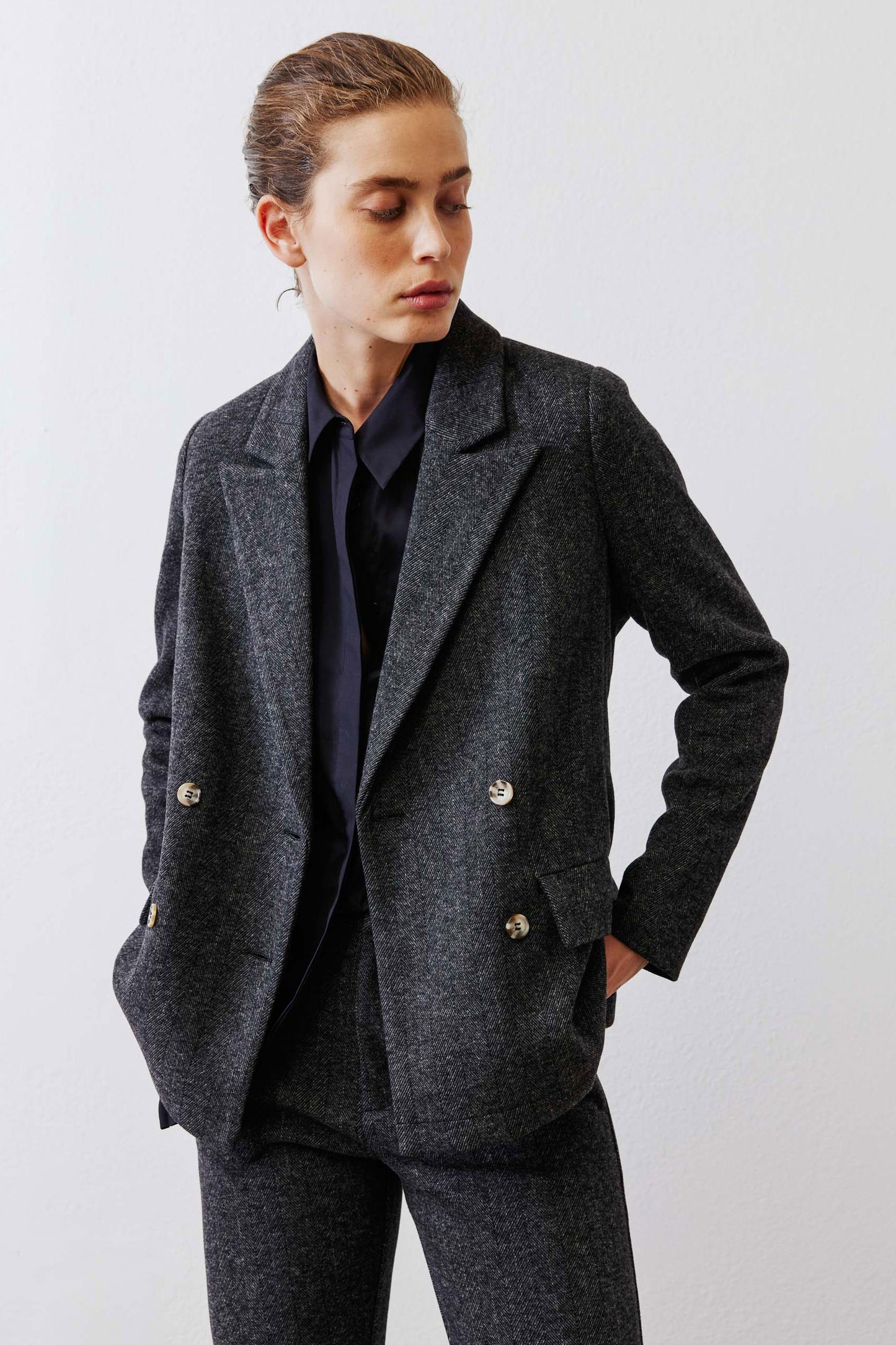 Charcoal herringbone blazer detail view, gold button closures and notch lapels