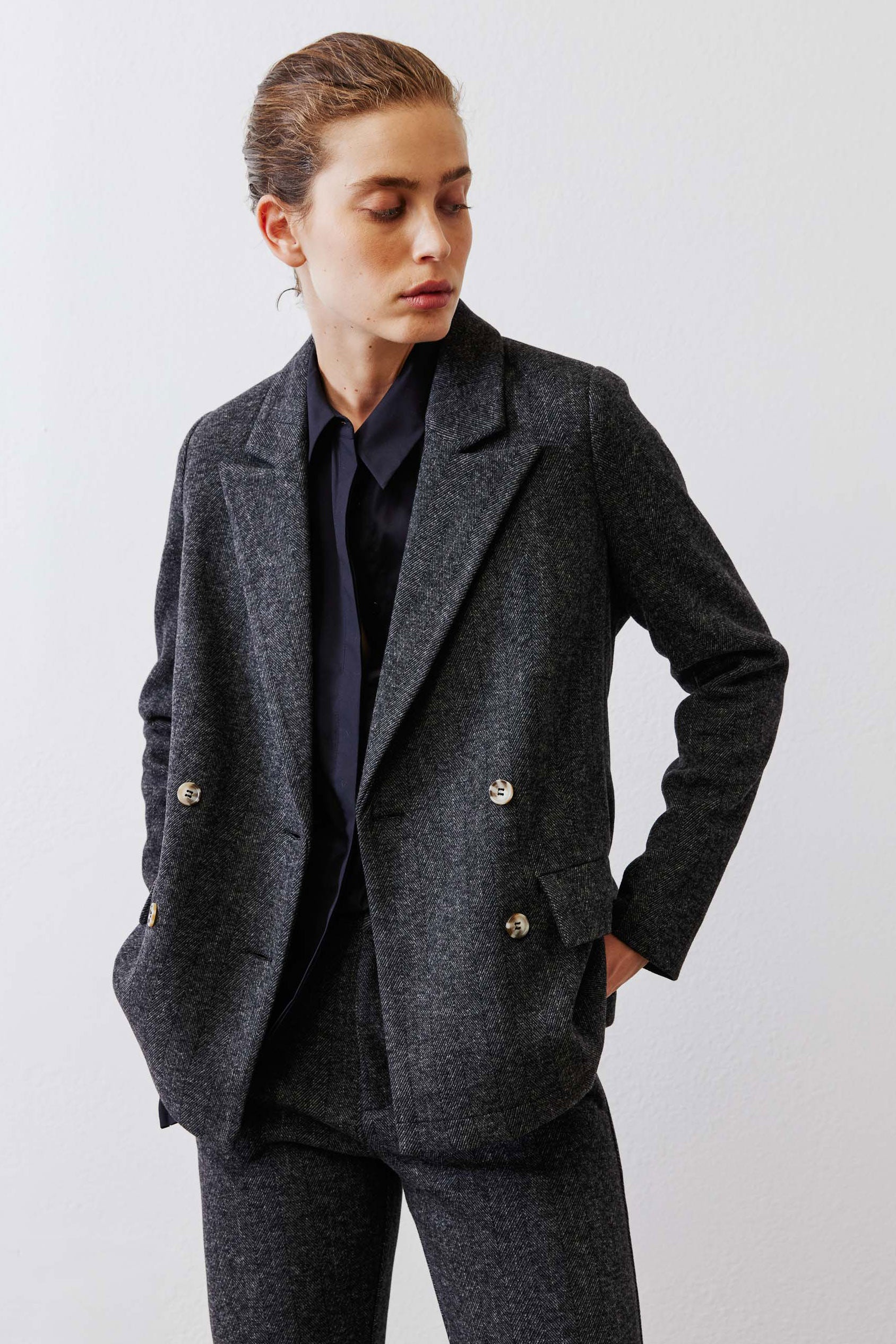 Charcoal herringbone blazer detail view, gold button closures and notch lapels