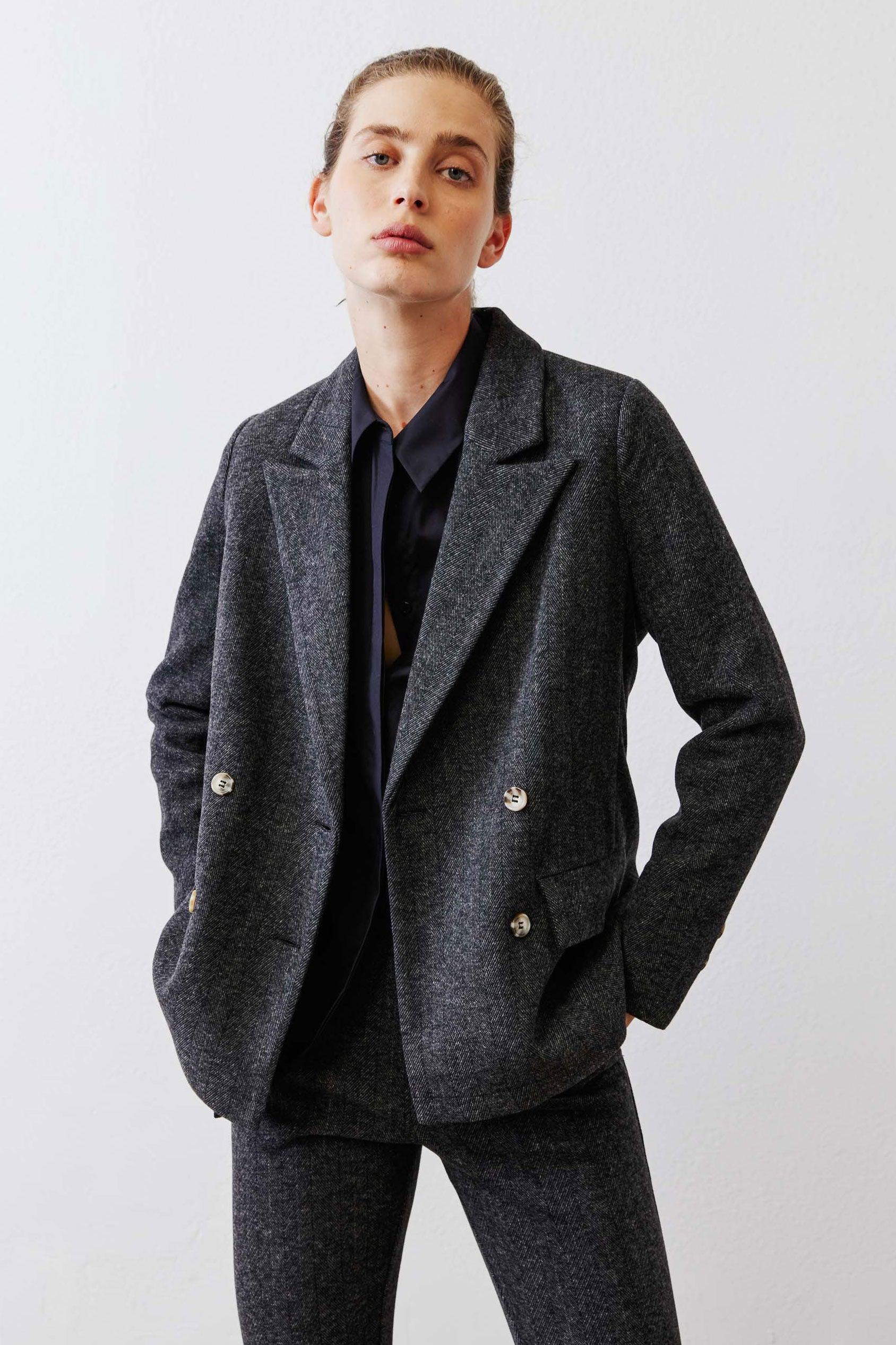 Charcoal herringbone blazer with gold buttons, notch lapels, and long sleeves