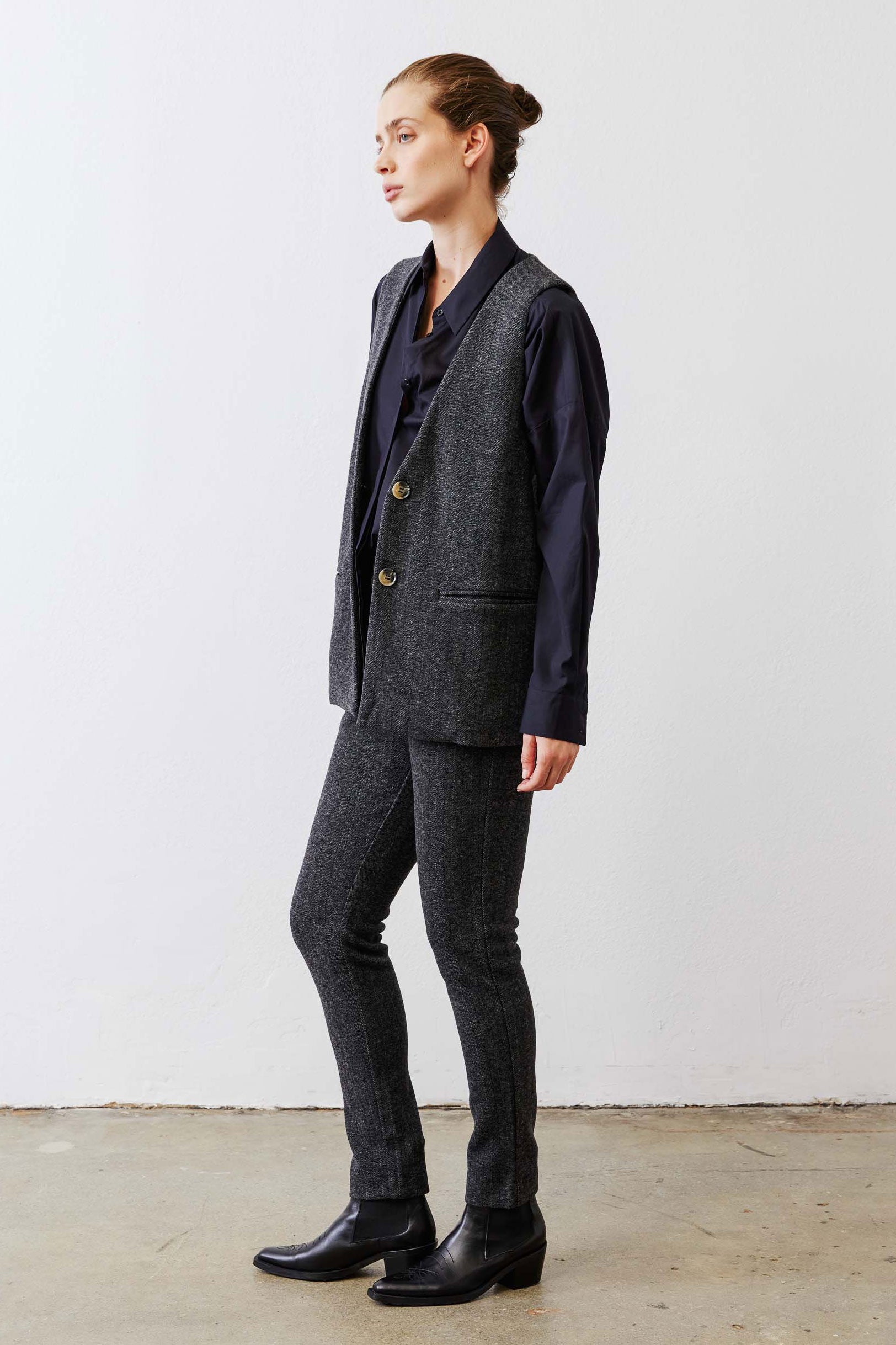 Charcoal longline herringbone vest shown from side with gold button closure