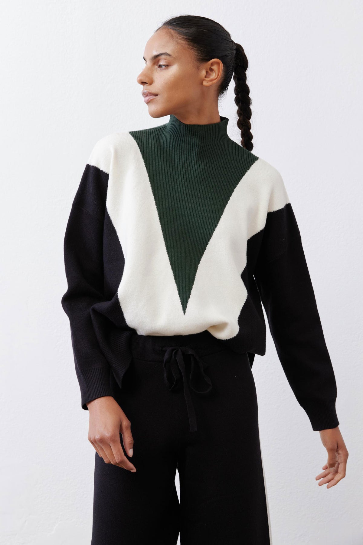 Turtleneck knit sweater with chevron colorblocking in forest green, cream, and black.