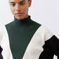 Turtleneck knit sweater close-up, forest green center with cream V and black side panel.
