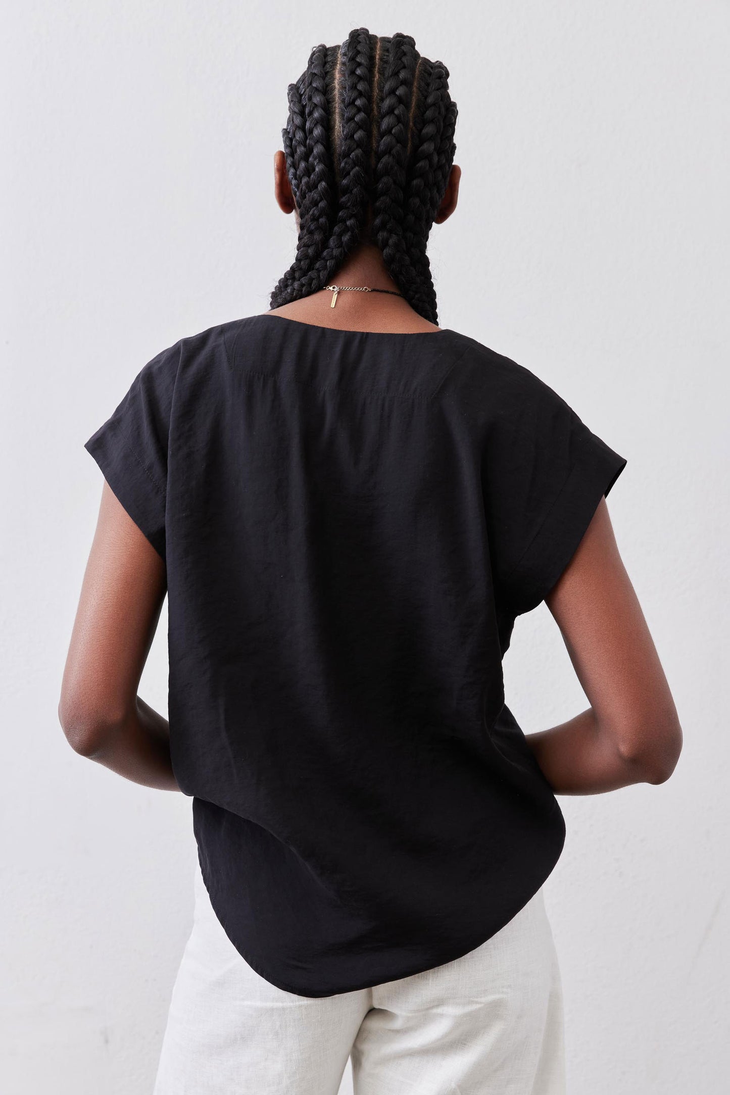 Black poplin top back view with draped center and short sleeves