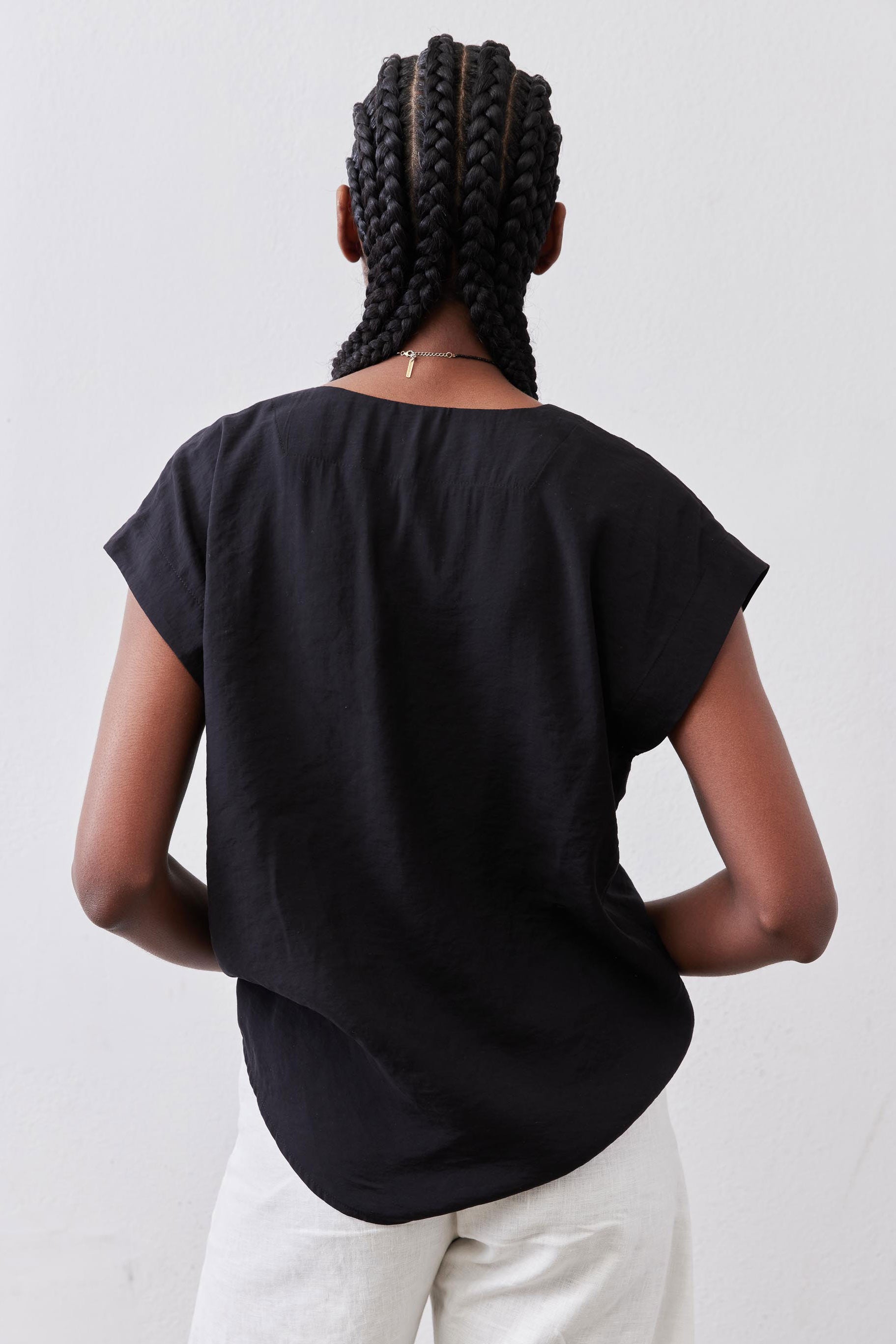 Black poplin top back view with draped center and short sleeves
