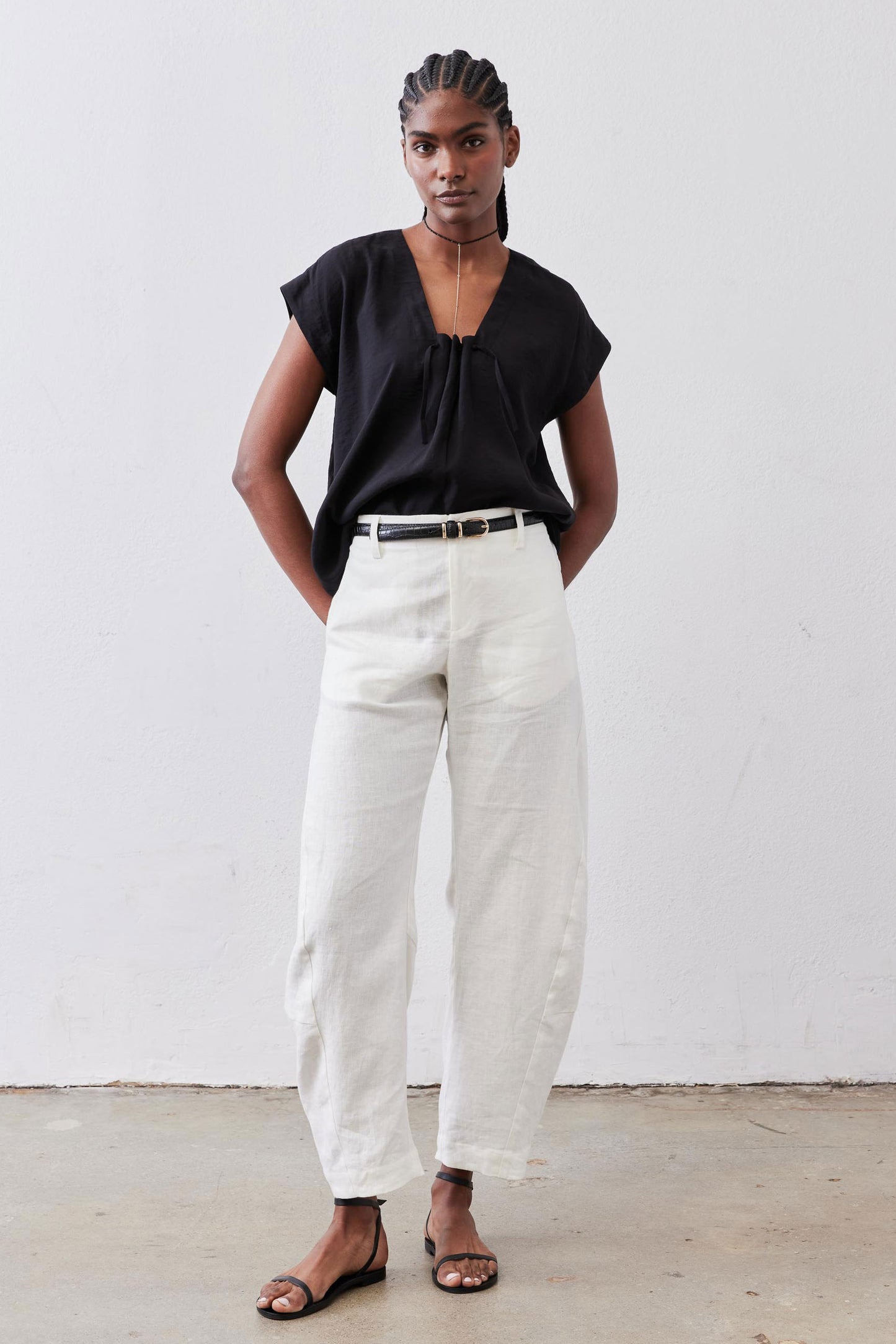 Black cinched-neck poplin top with short sleeves and gathered front, worn tucked into pants