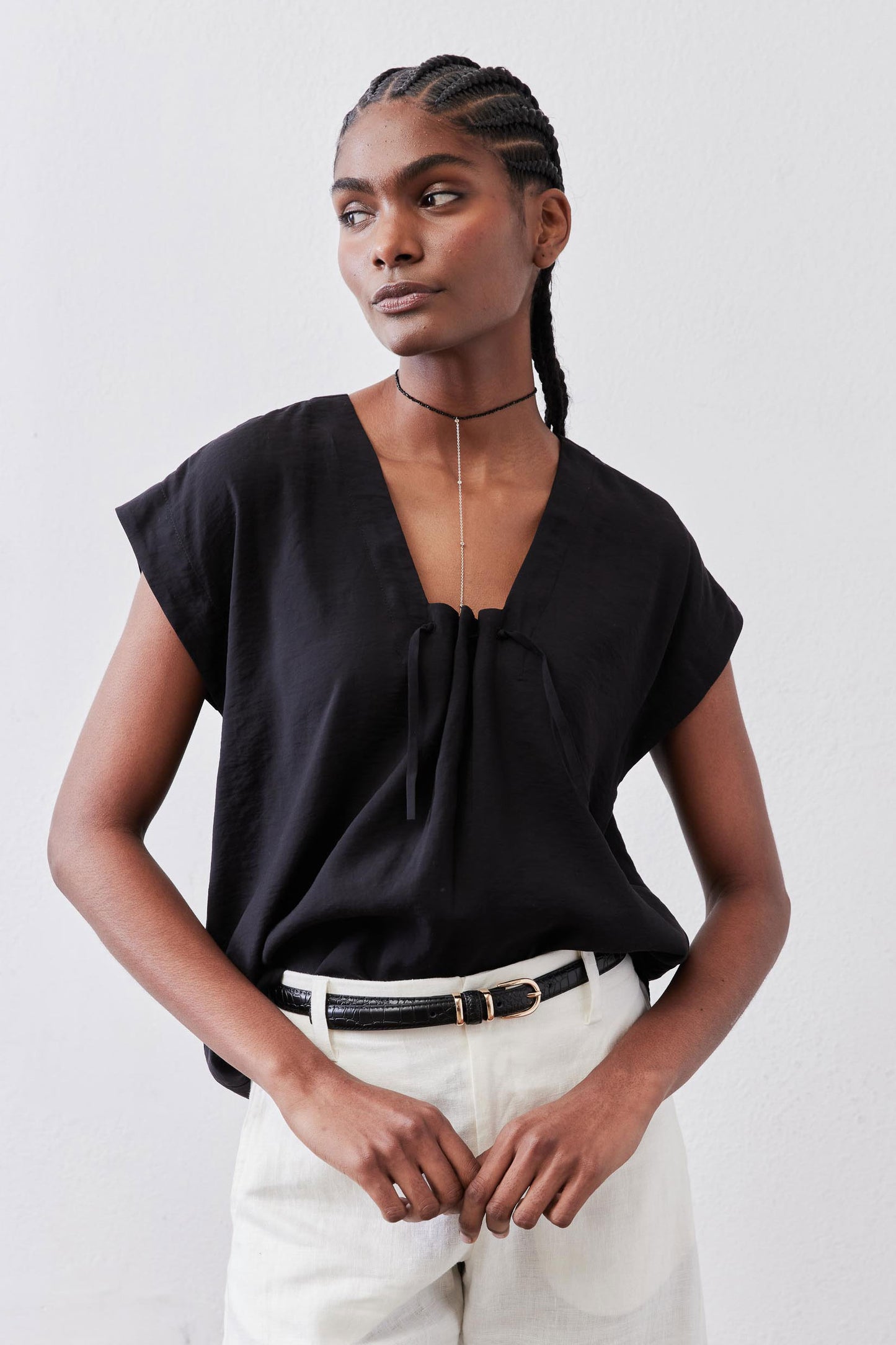Black cinched-neck poplin top with gathered center front and short sleeves, close-up
