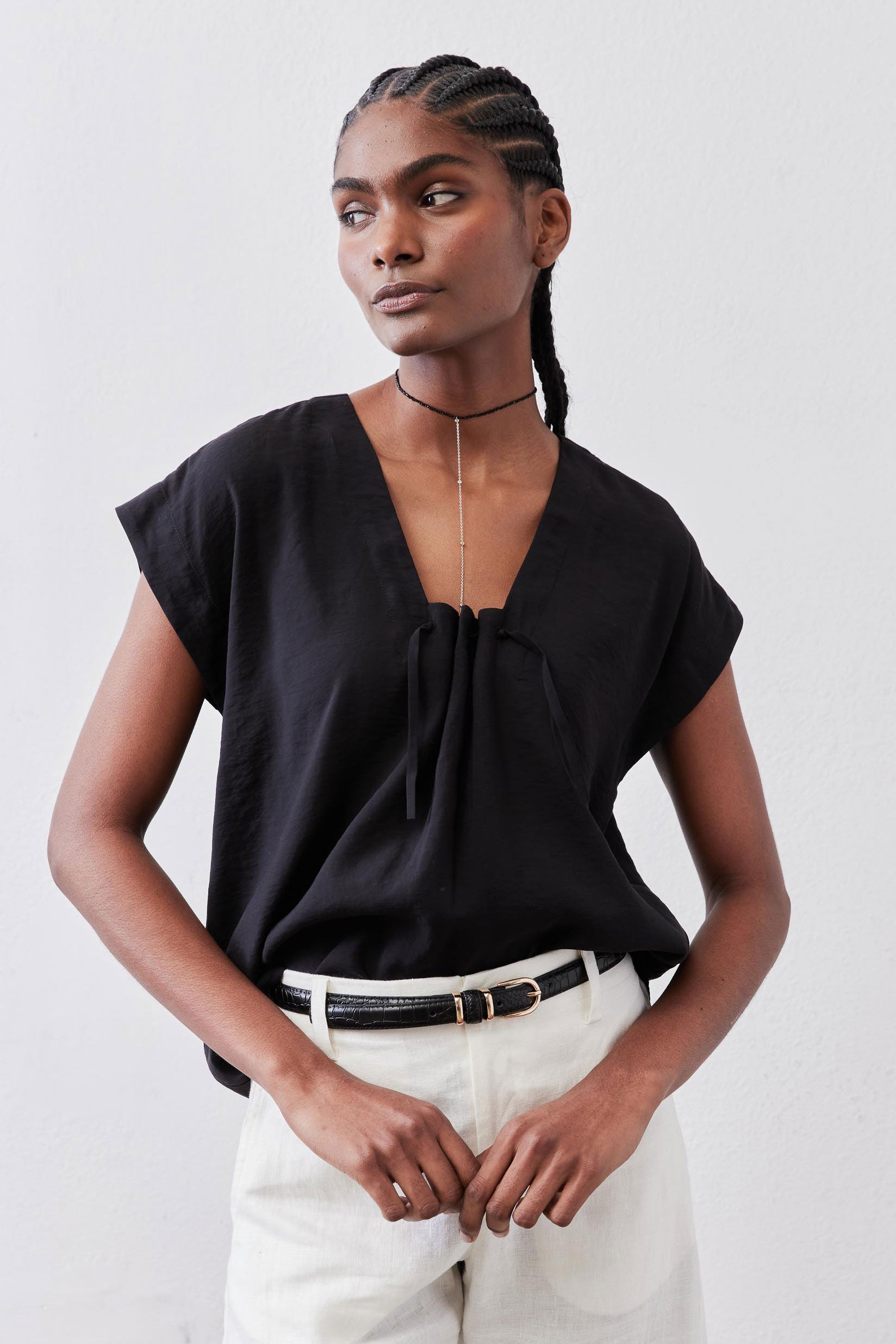 Black cinched-neck poplin top with gathered center front and short sleeves, close-up