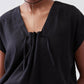 Black poplin top close-up showing cinched V neckline with gathered fabric at center