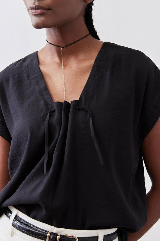 Black poplin top close-up showing cinched V neckline with gathered fabric at center