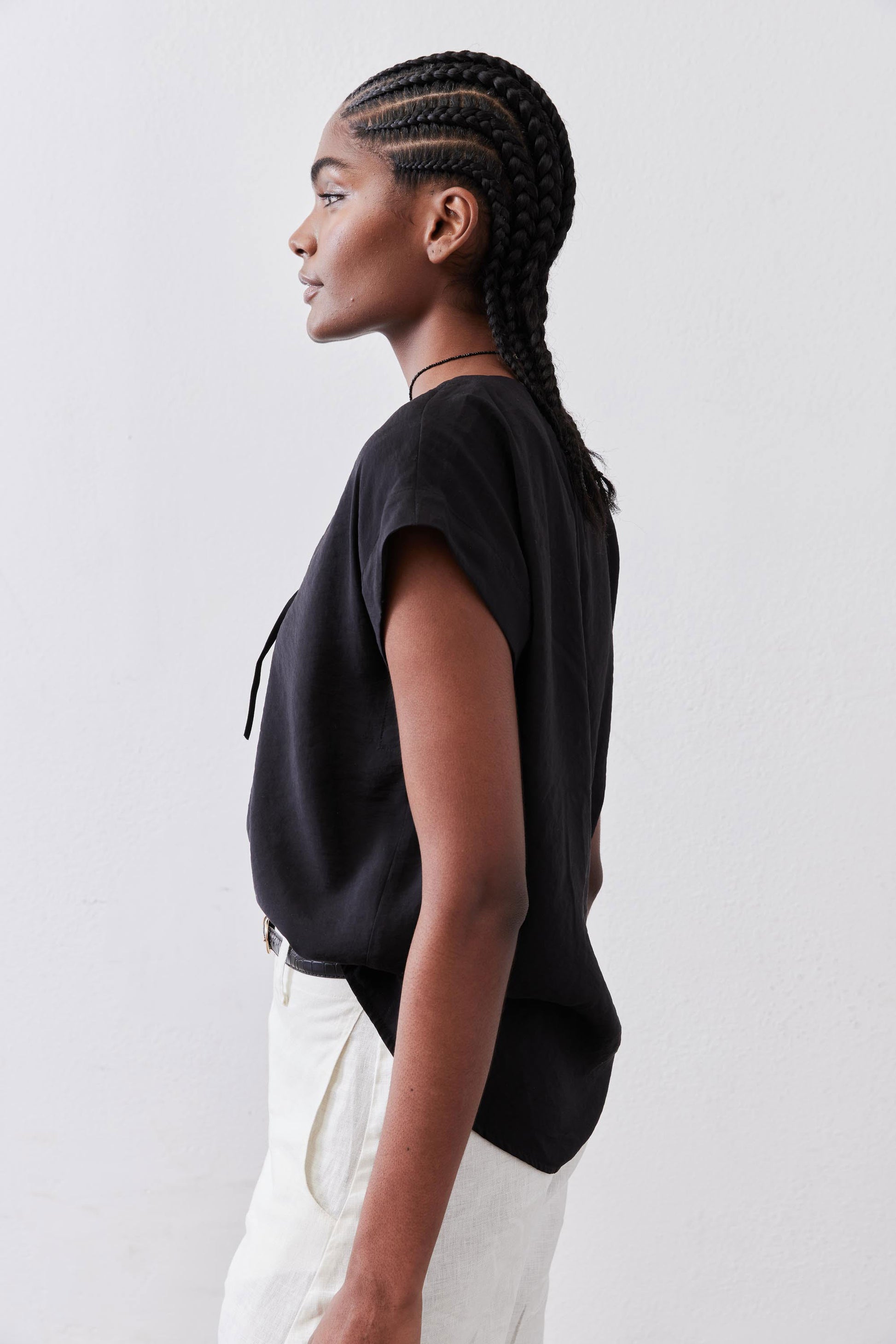 Black poplin top with cinched V back detail and short sleeves, side view