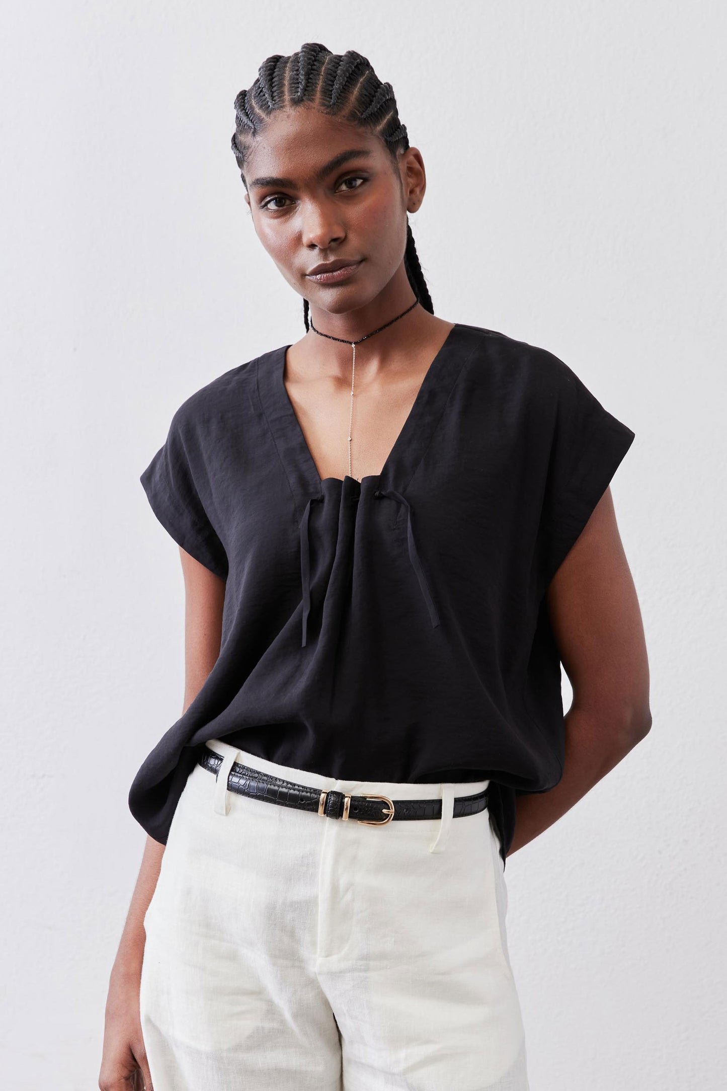 Black poplin top with cinched V neckline and short sleeves, draped gathered front