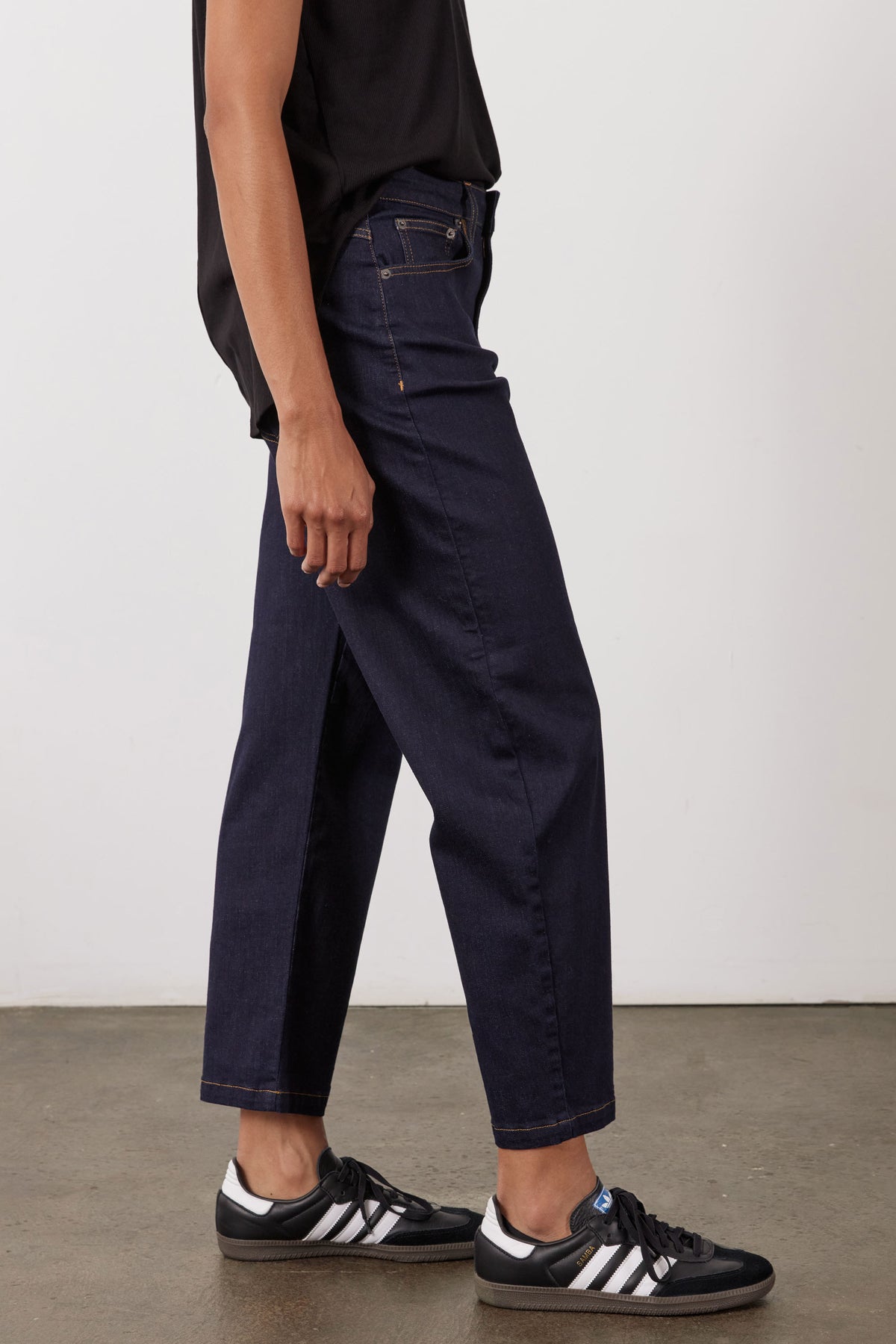 Dark wash barrel-leg jeans, side view, button waist, belt loops and front pockets.