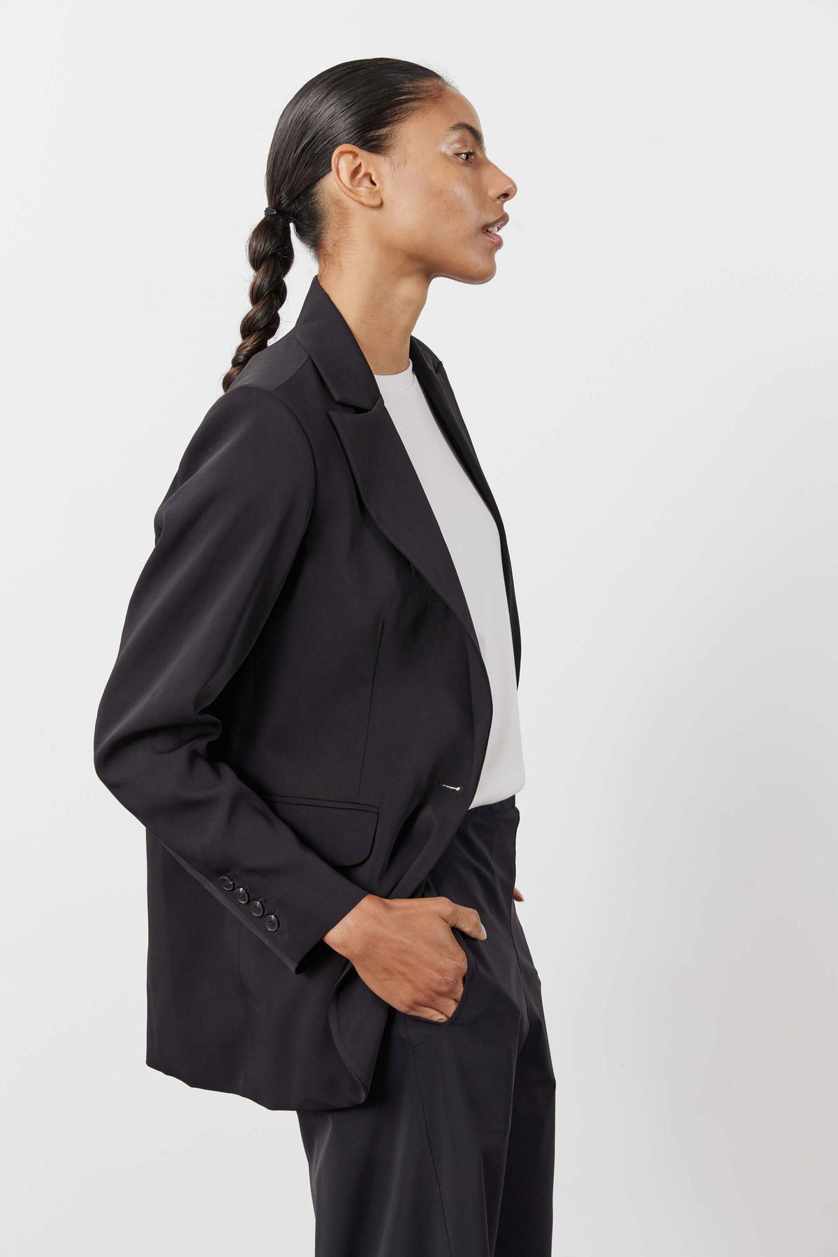 Black single-breasted blazer with notch lapel and flap pocket, side profile