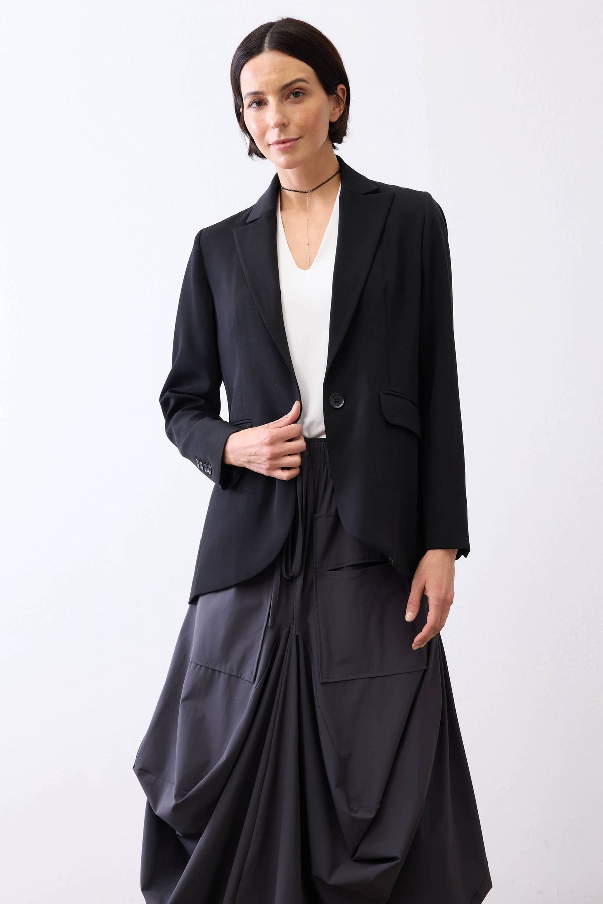 Classic black blazer with notch lapels and front pockets, worn with a draped dark skirt