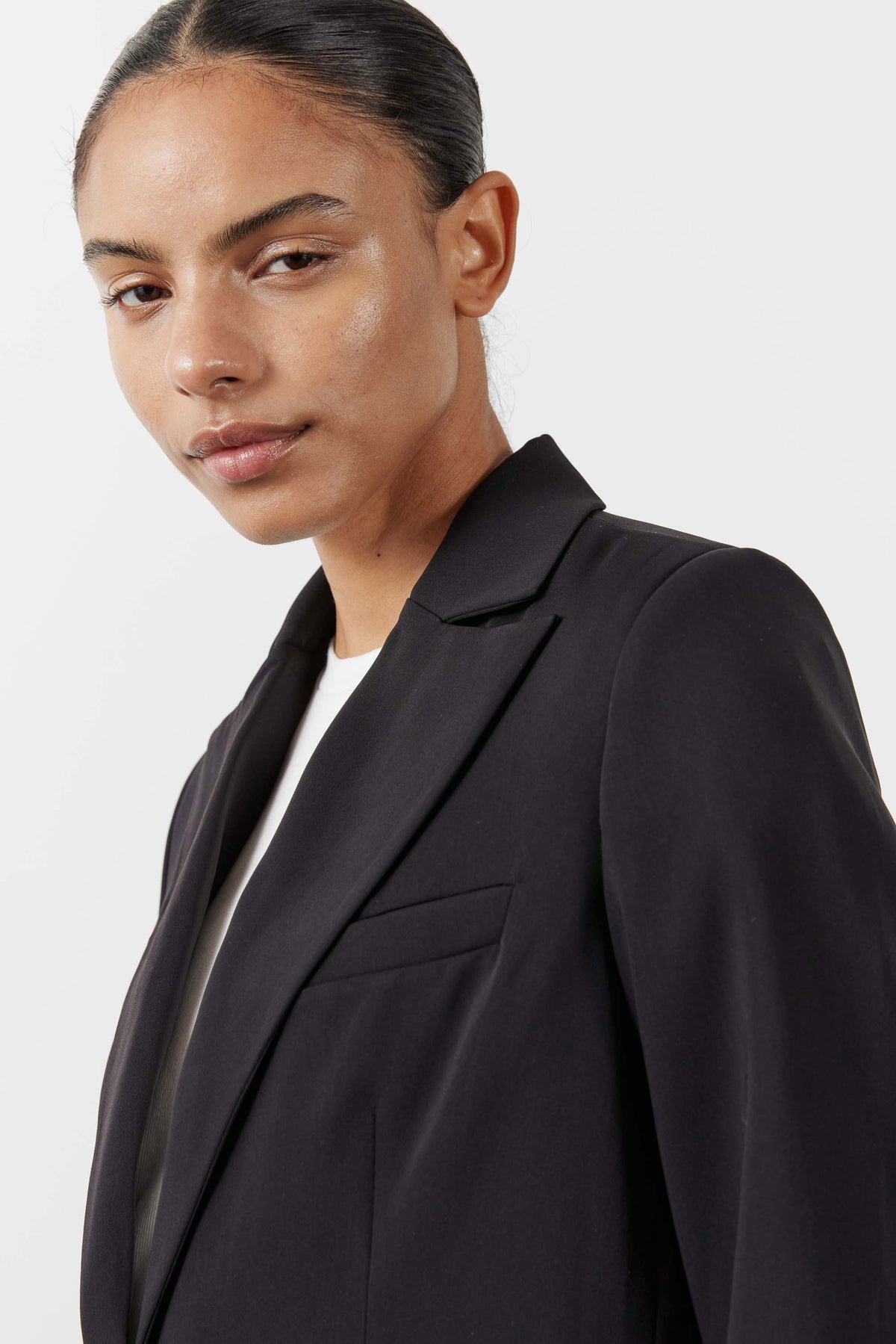 Black blazer lapels and chest pocket, worn over a light top, close-up
