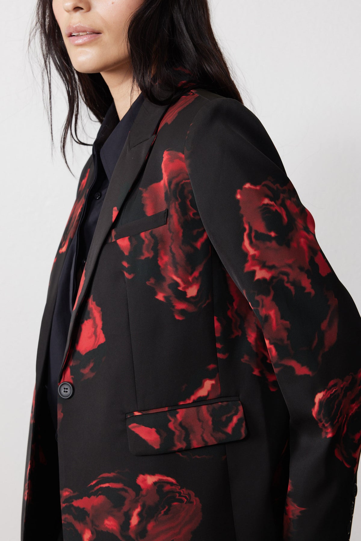 Black blazer shoulder and lapel with red rose print and visible button