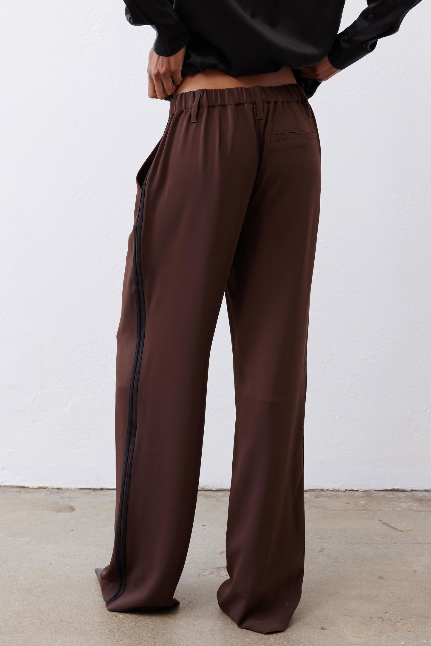Dark brown wide-leg trousers with gathered elastic waistband and black side stripe