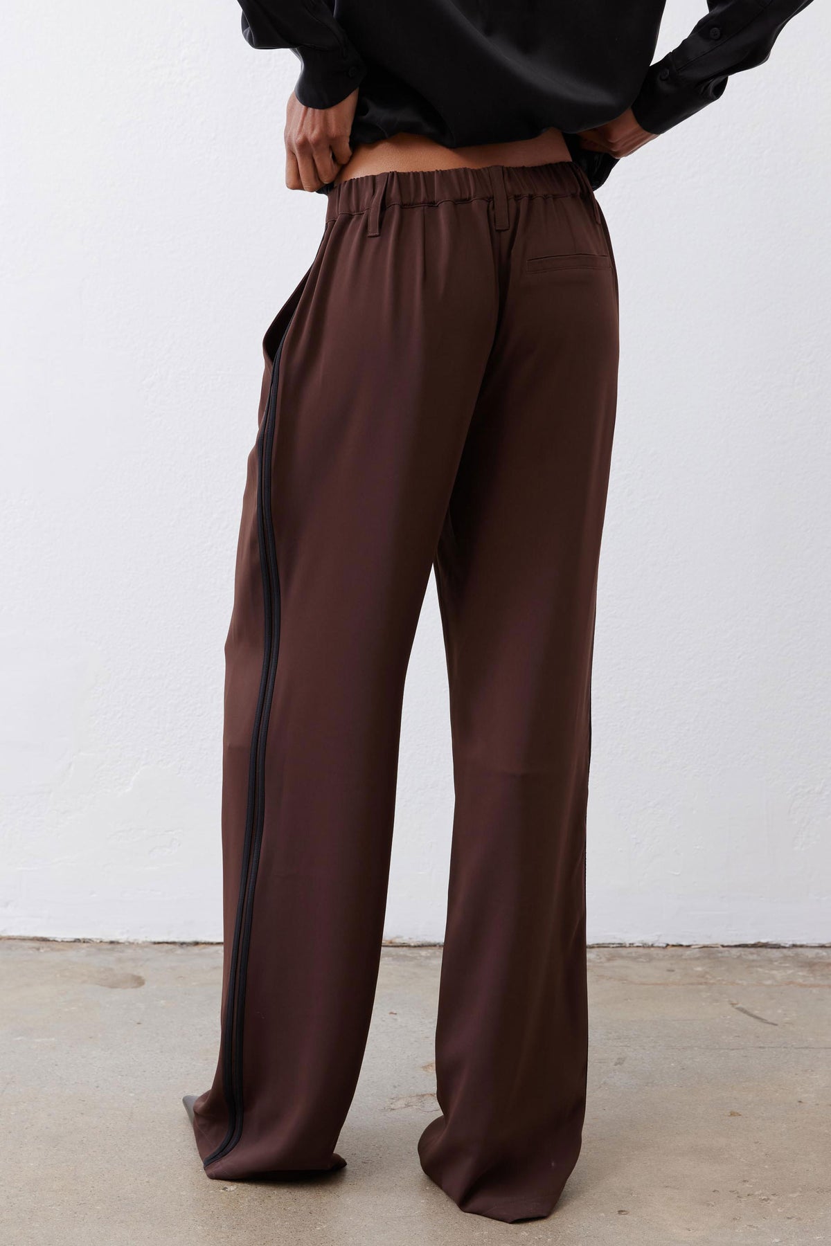 Dark brown wide-leg trousers with gathered elastic waistband and black side stripe