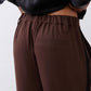 Close-up of dark brown pleated waist with elastic band and front pockets