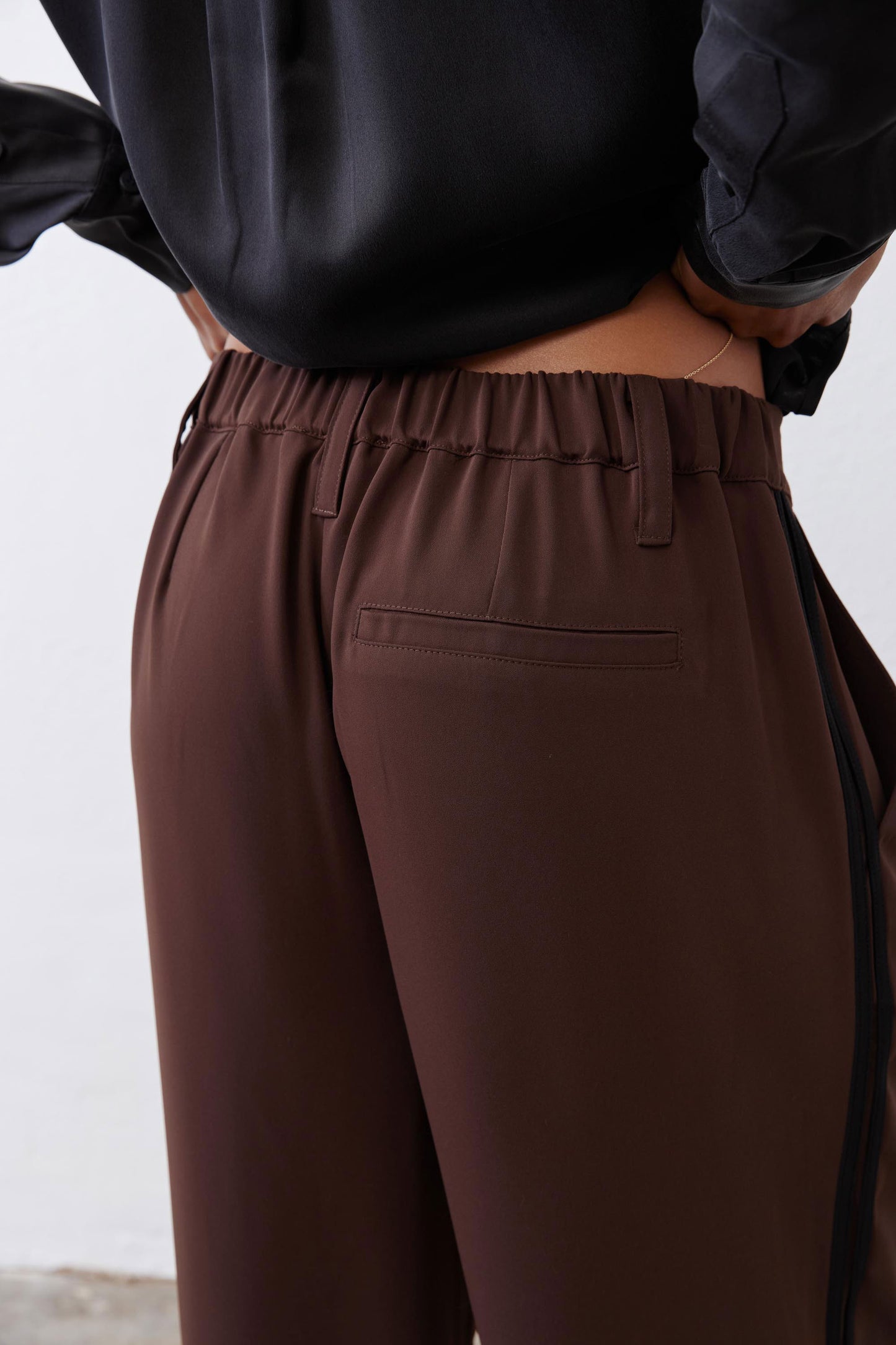 Close-up of dark brown pleated waist with elastic band and front pockets