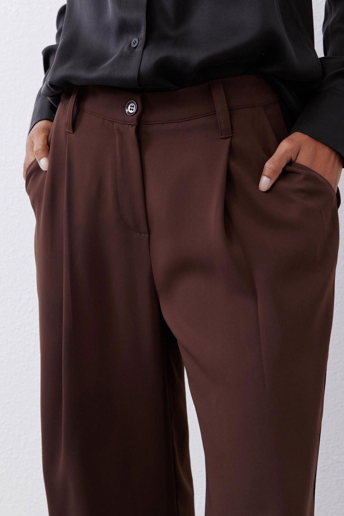 Close-up of dark brown button-front wide-leg pants with belt loops and side seam