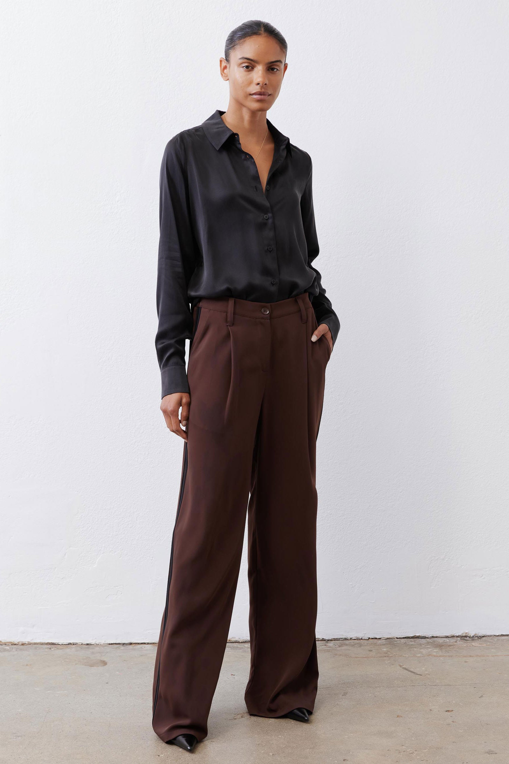 Brown wide-leg trousers with pleats, button front, and subtle black side stripe