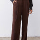 Close view of dark brown wide-leg pants with belt loops and button waist