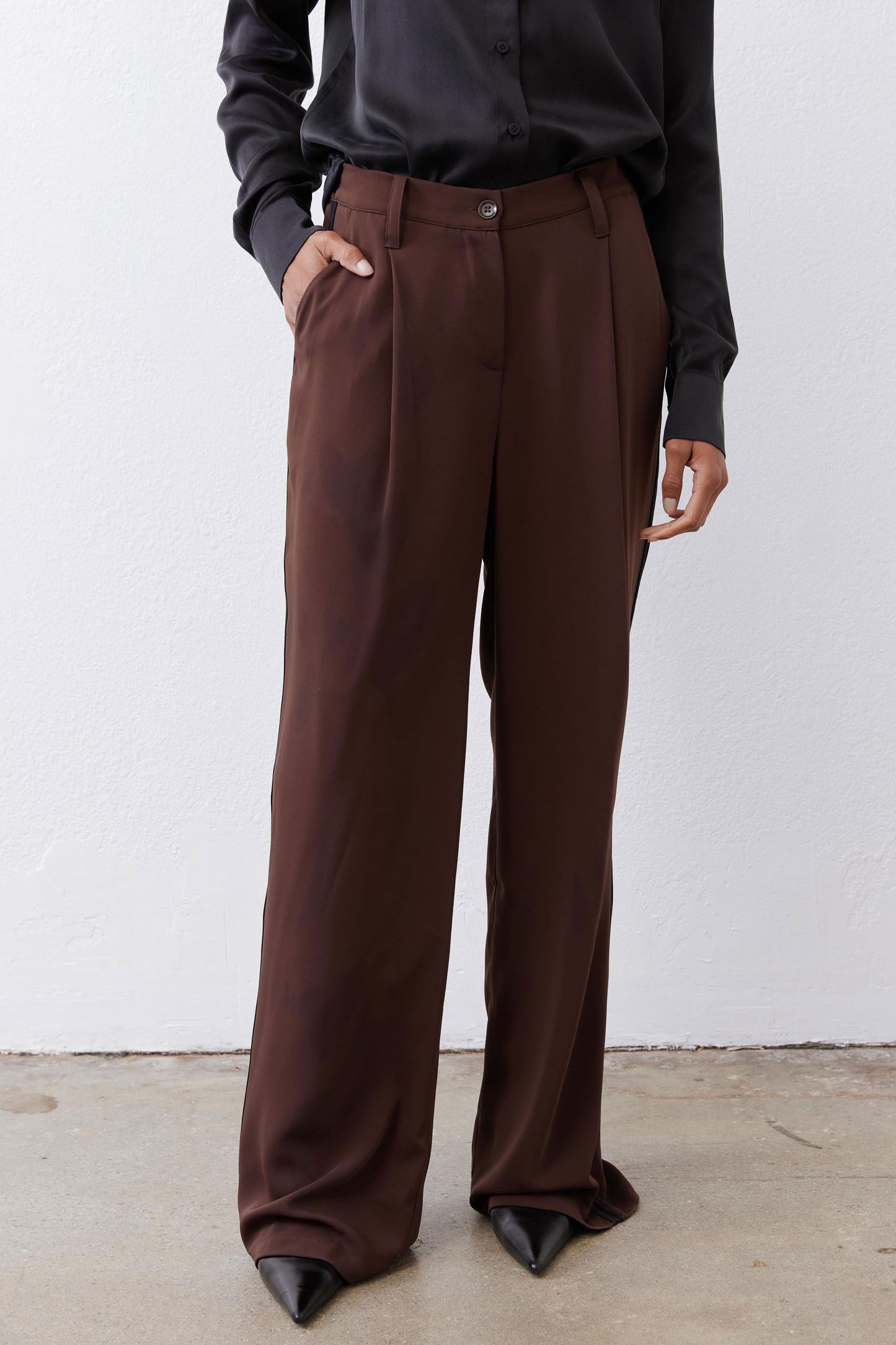 Close view of dark brown wide-leg pants with belt loops and button waist