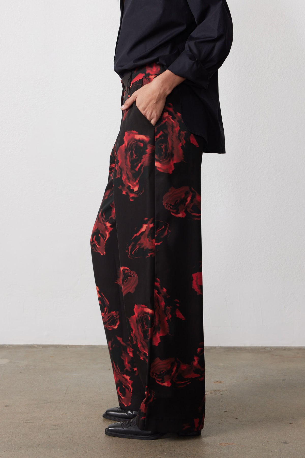 Wide-leg pants with black base and red rose pattern, side view