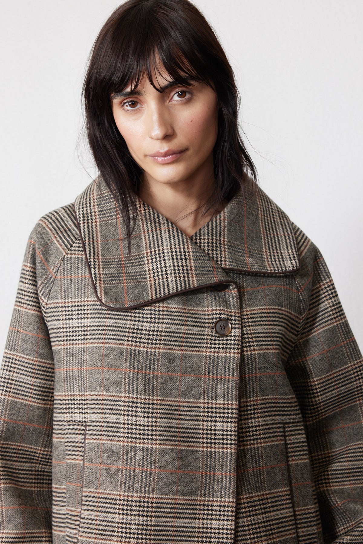 Brown plaid asymmetric collared jacket close-up, button and yoke detail