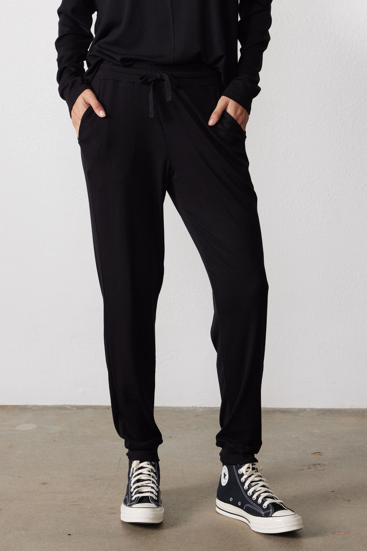 Black pajama pants with drawstring waist, side pockets, and tapered cuffs