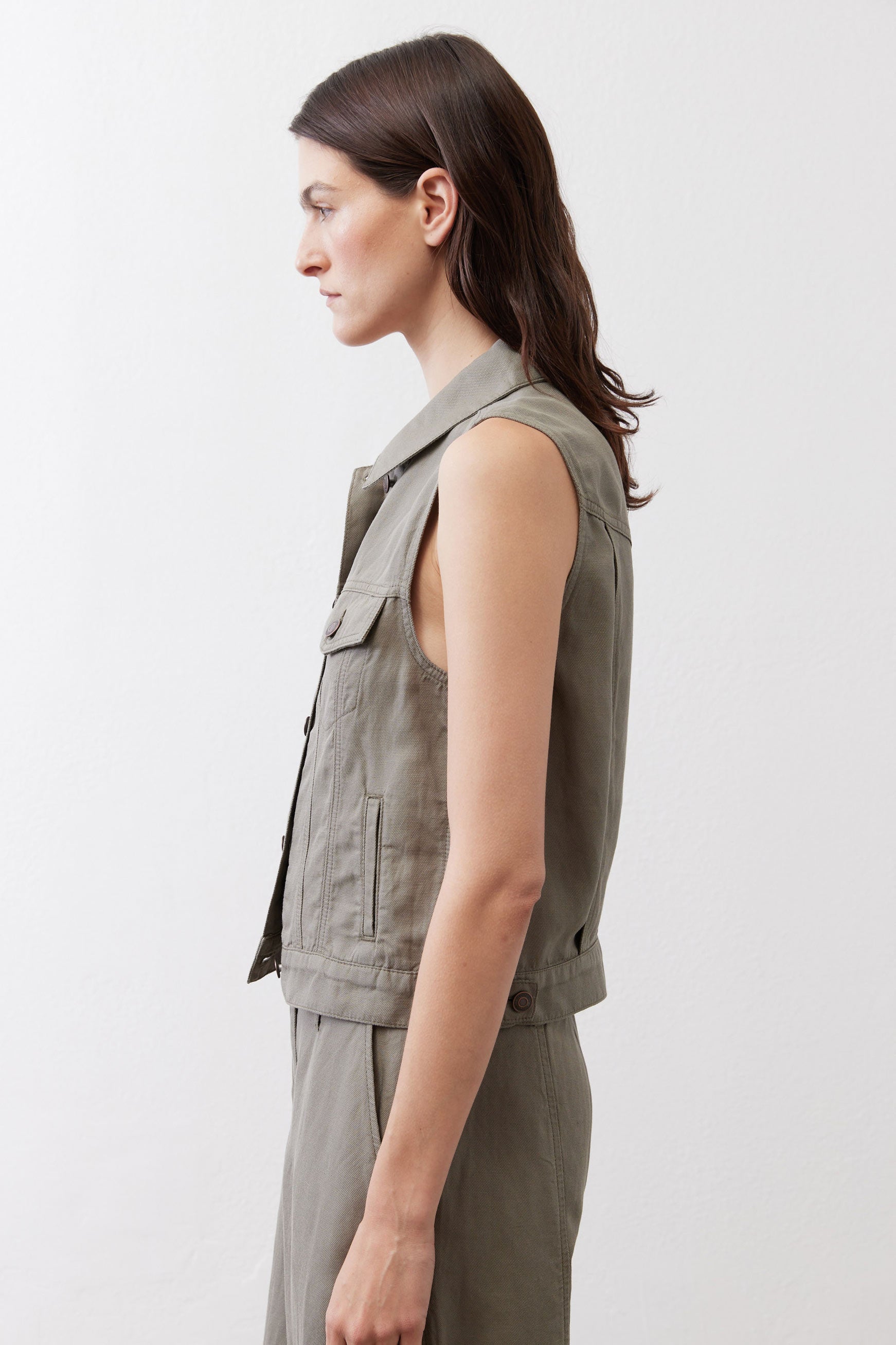 Olive green cropped task vest side view, sleeveless with button front and pockets