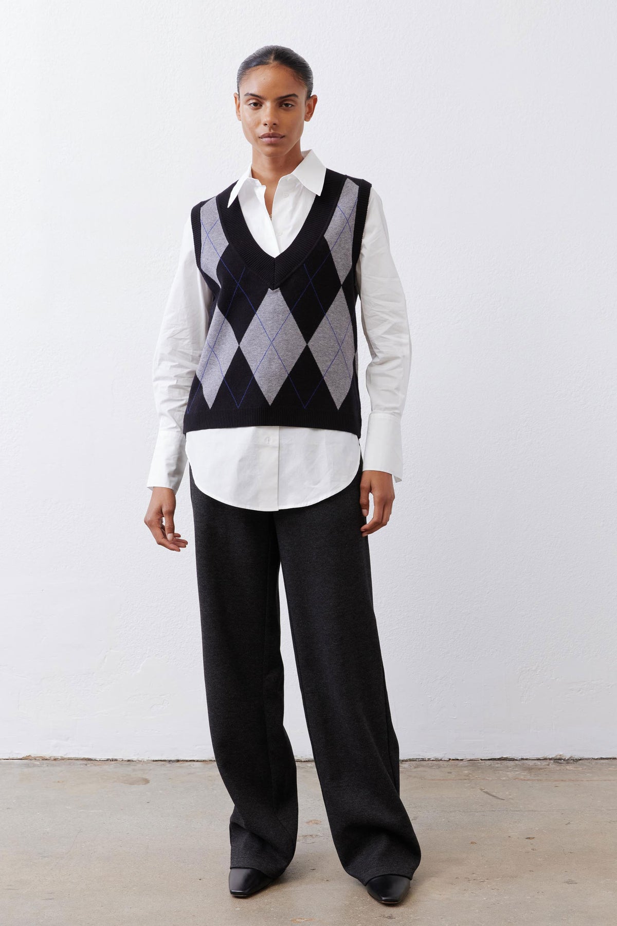 White button-down tunic worn under black argyle V-neck sweater vest