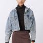 Washed-blue denim jacket with chest pockets and buttoned front over turtleneck