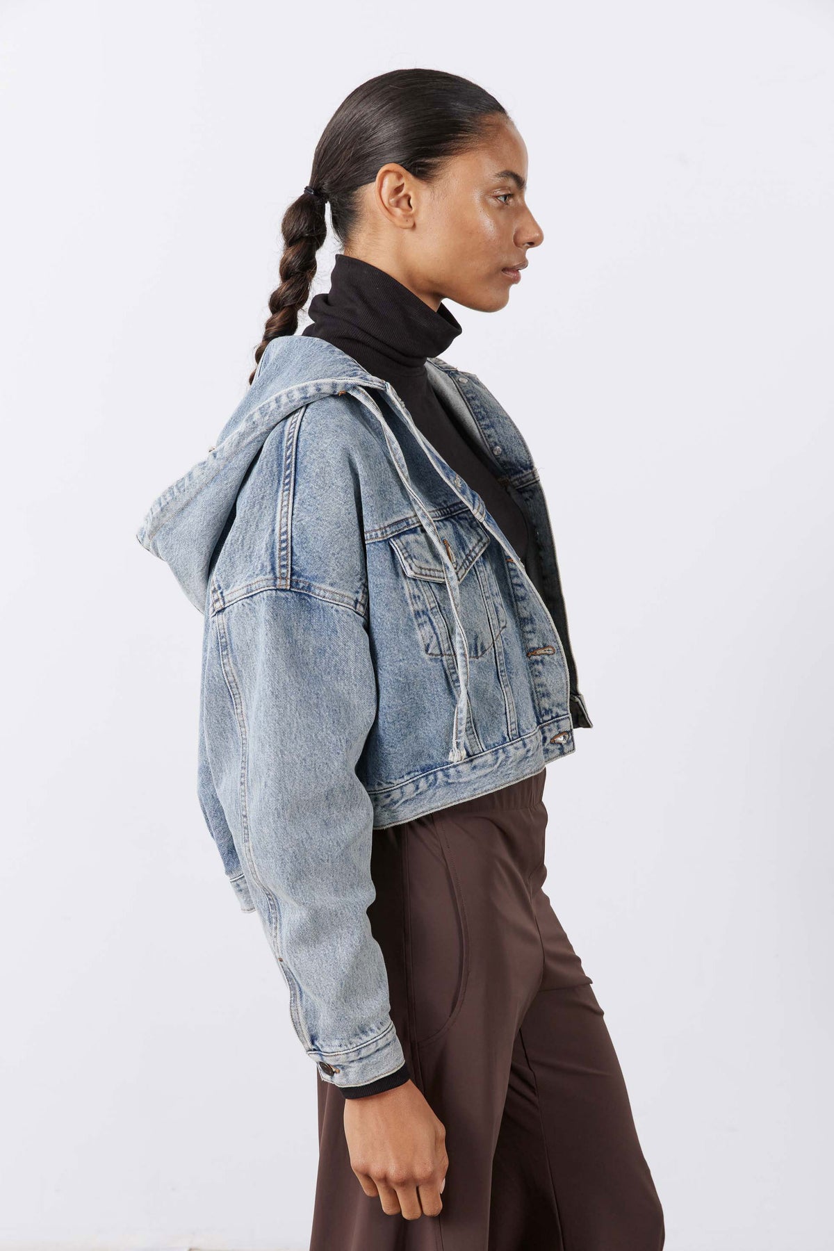 Washed-blue denim jacket, side view with buttoned chest and hood opening