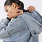 Washed-blue denim jacket close-up with hood seam and collar detail