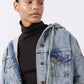 Washed-blue denim jacket with hood and buttoned chest, worn over black turtleneck