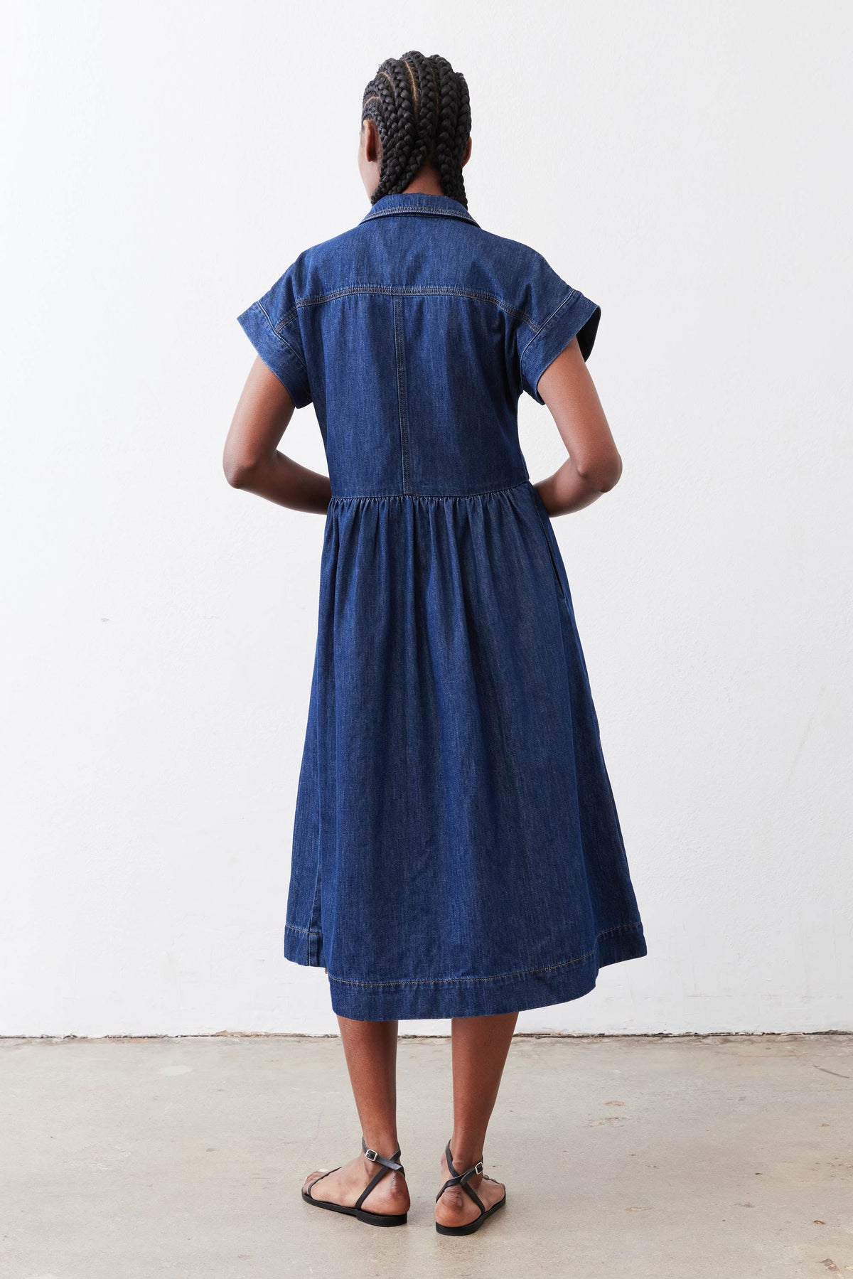 Back view of medium-wash denim shirt dress with gathered waist and short sleeves
