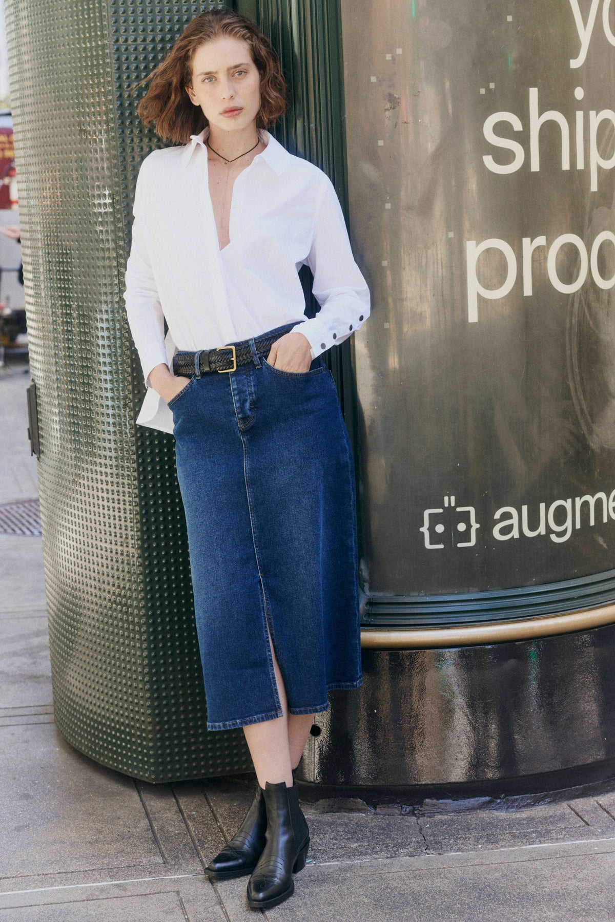 Women’s denim midi skirt in medium wash blue with front slit and patch pockets, belted
