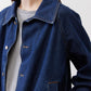 Denim cropped swing jacket close-up: buttoned collar, chest pocket, and visible stitching