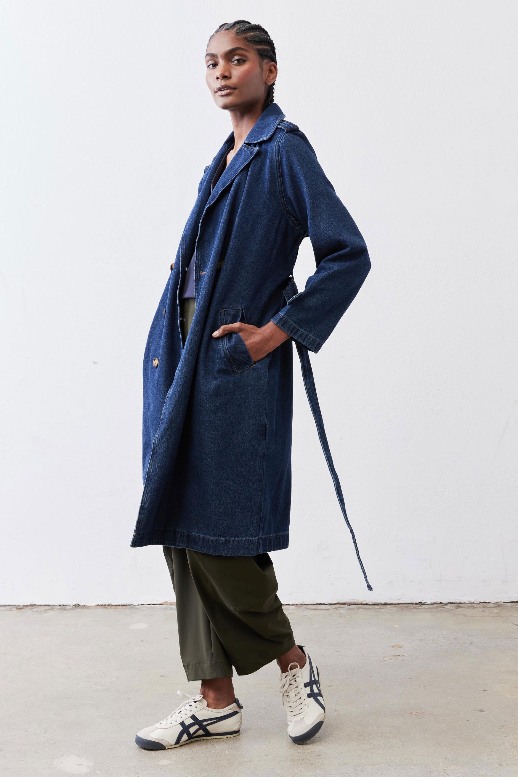 Navy denim trench coat with storm flap, long sleeves, and belted waist detail
