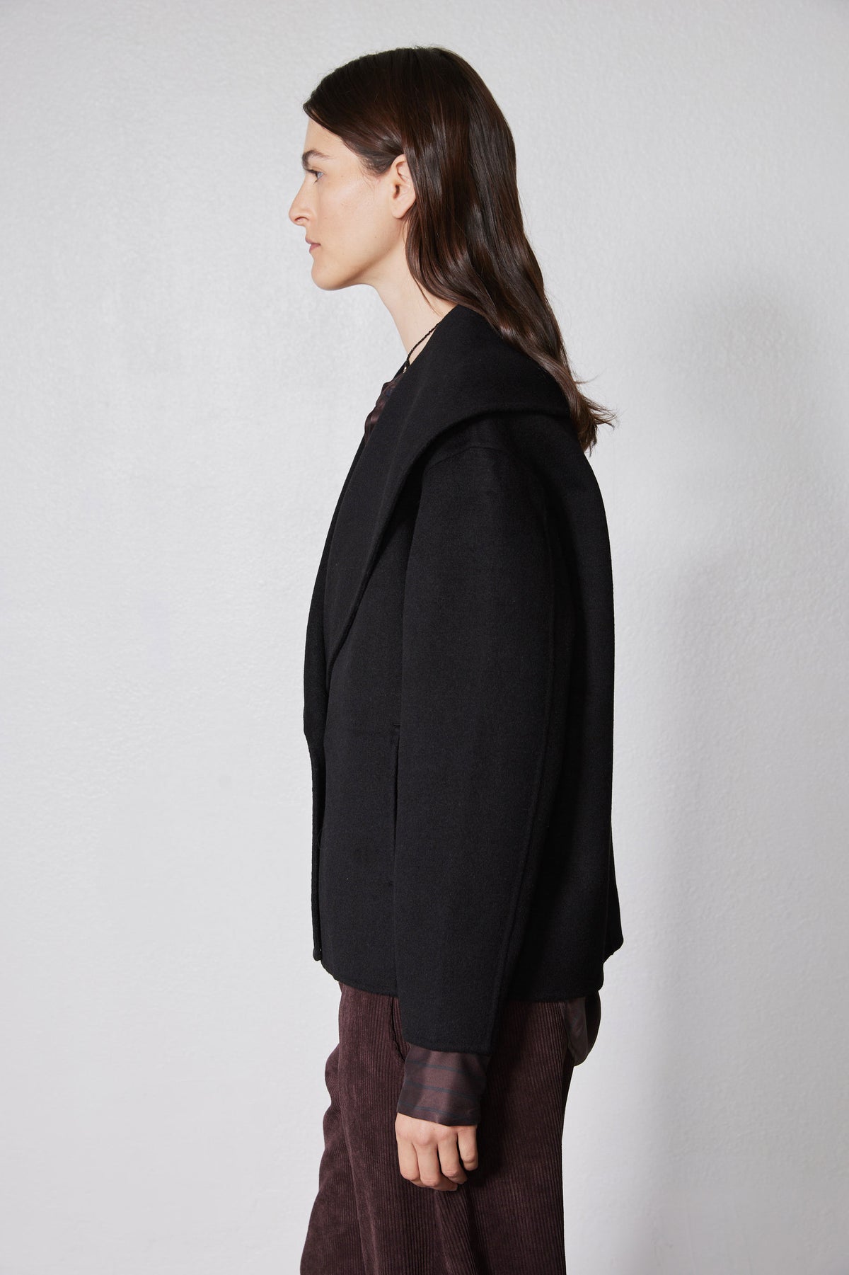 Black cropped wool coat in side view with structured shoulders and buttoned front