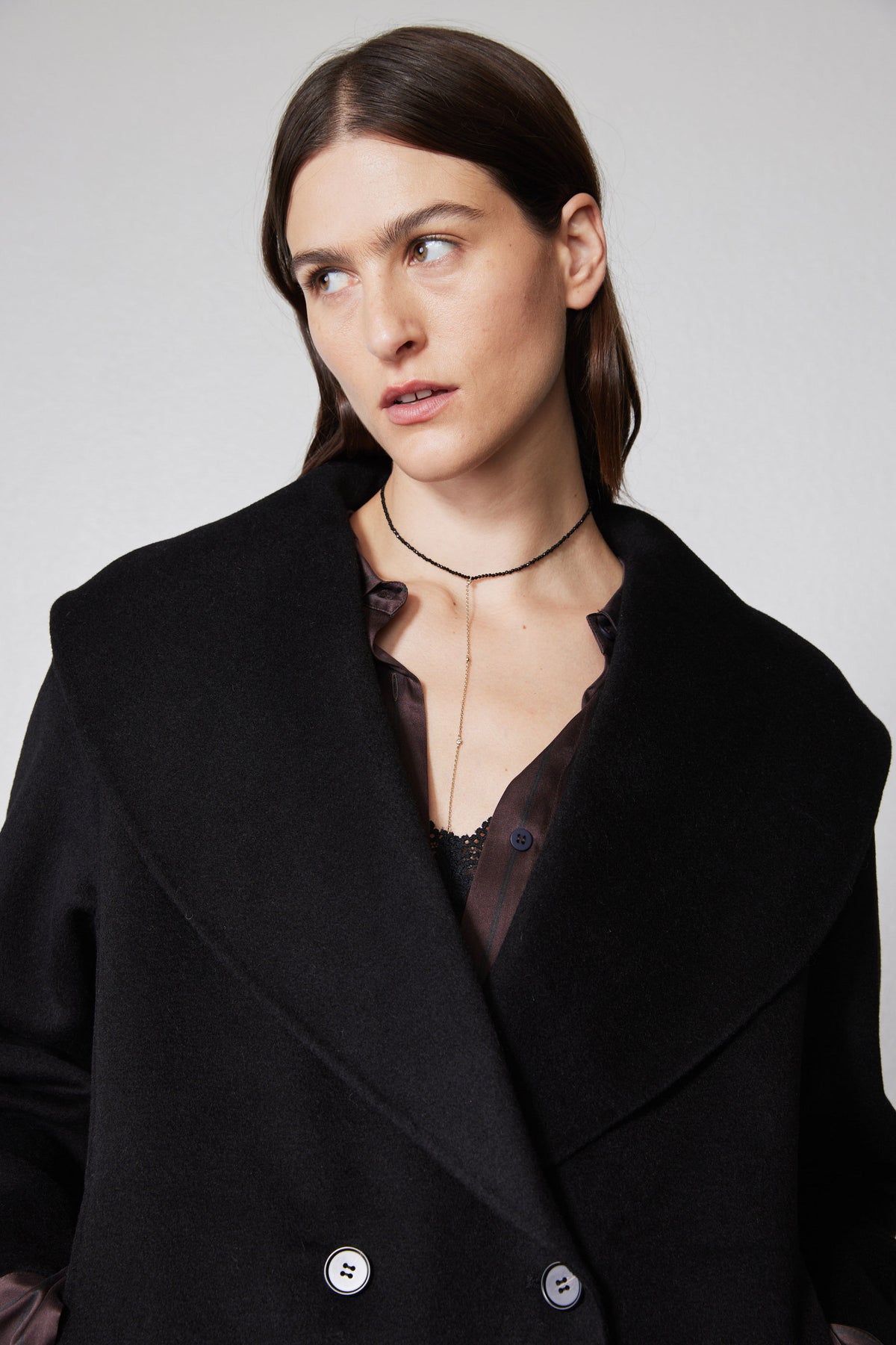 Black cropped wool coat close-up with wide collar, lapels, and two button details